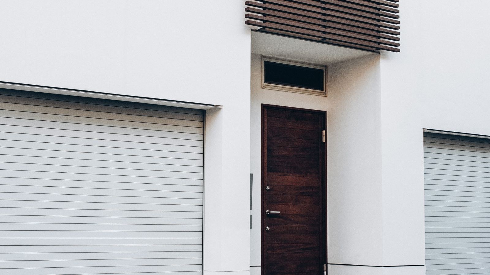 Exterior of a house showing a side entry door beside garage entrances