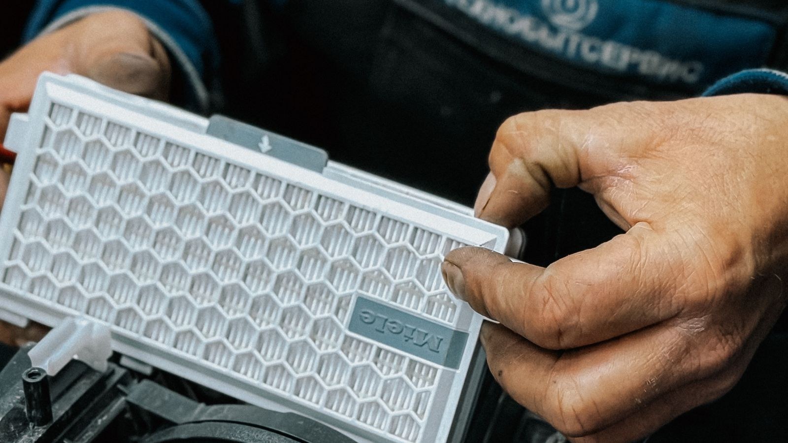 Hands removing a pleated HEPA filter from an air purifier for replacement