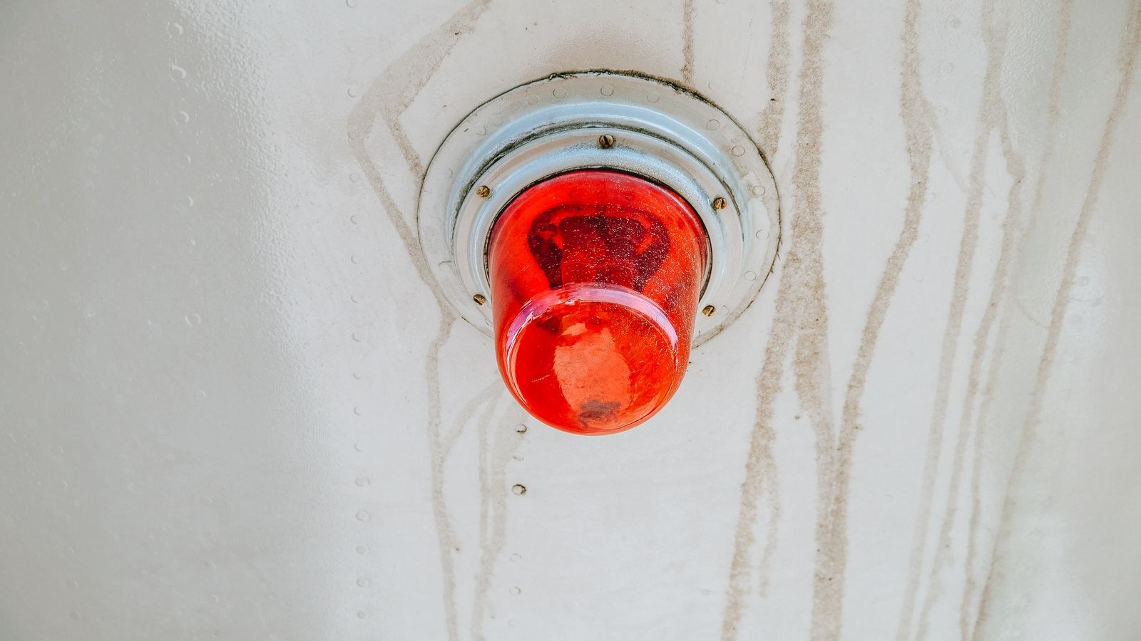 Red alarm warning light mounted on a metal surface