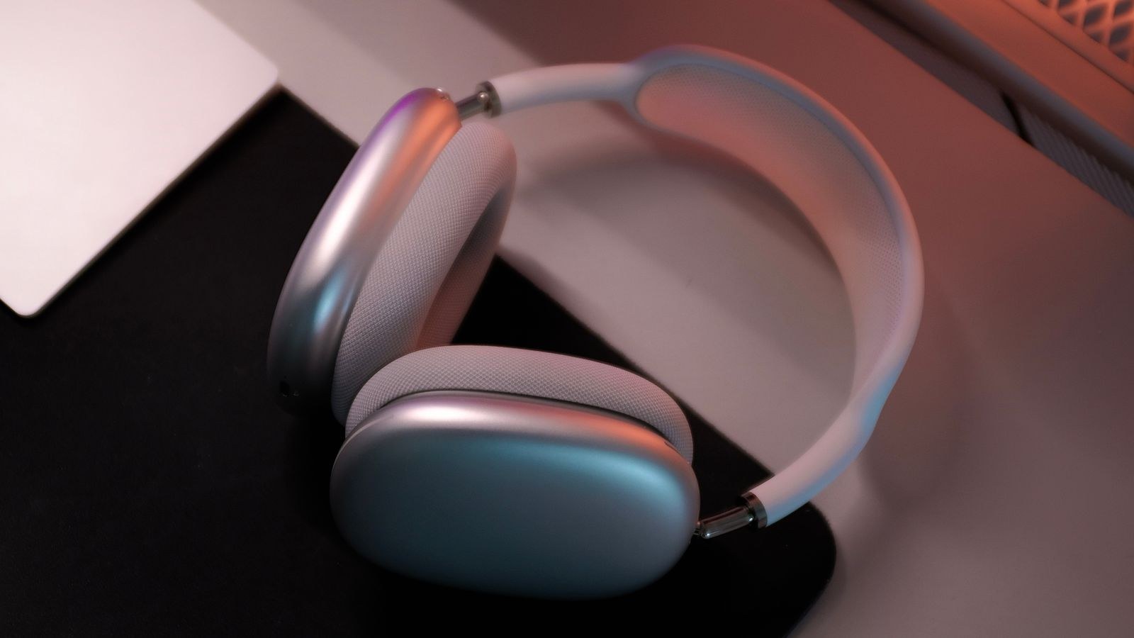 Wireless headphones resting on a desk under warm ambient lighting
