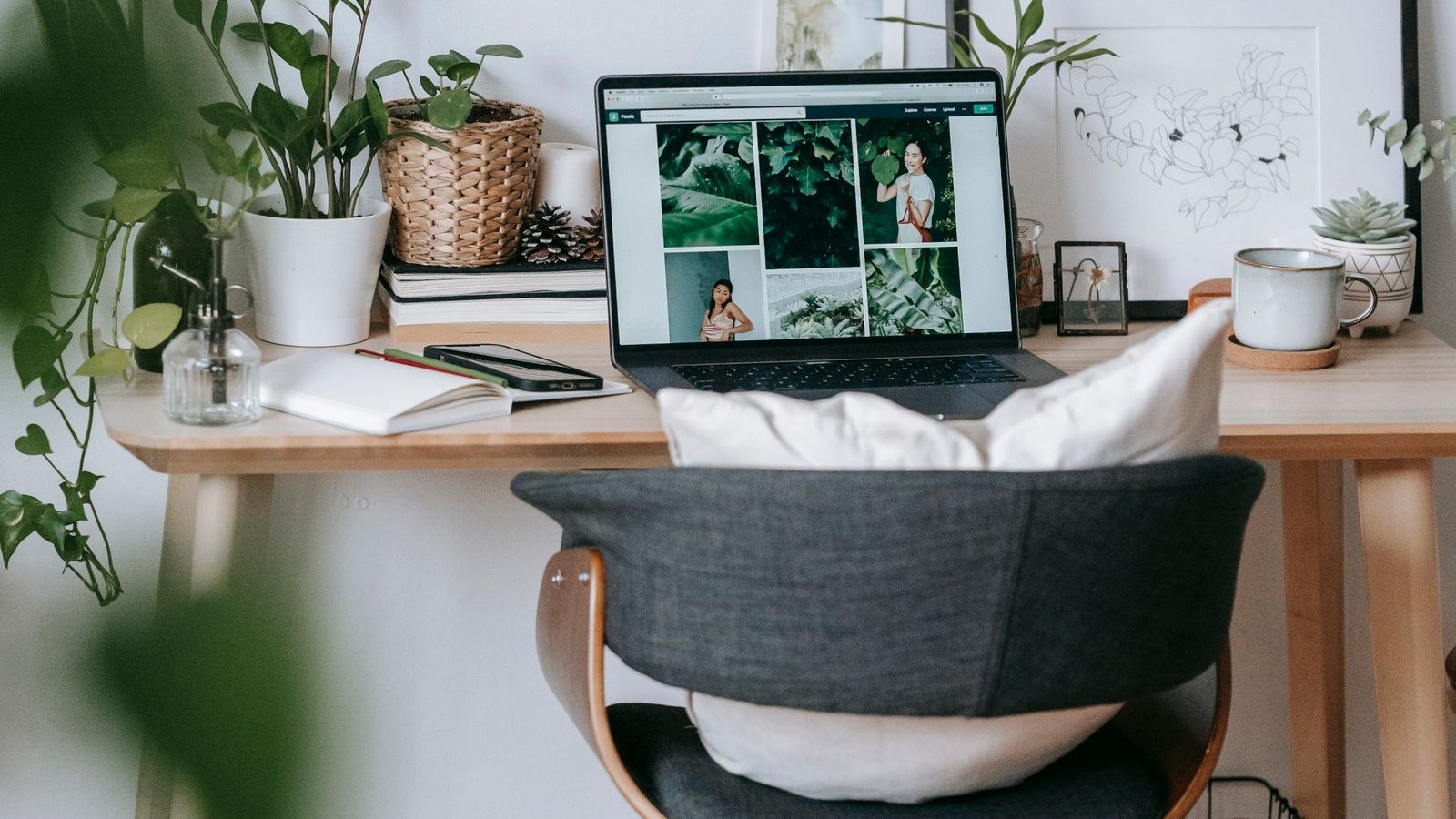 Compact workspace with a laptop and plants beside a window in a small room