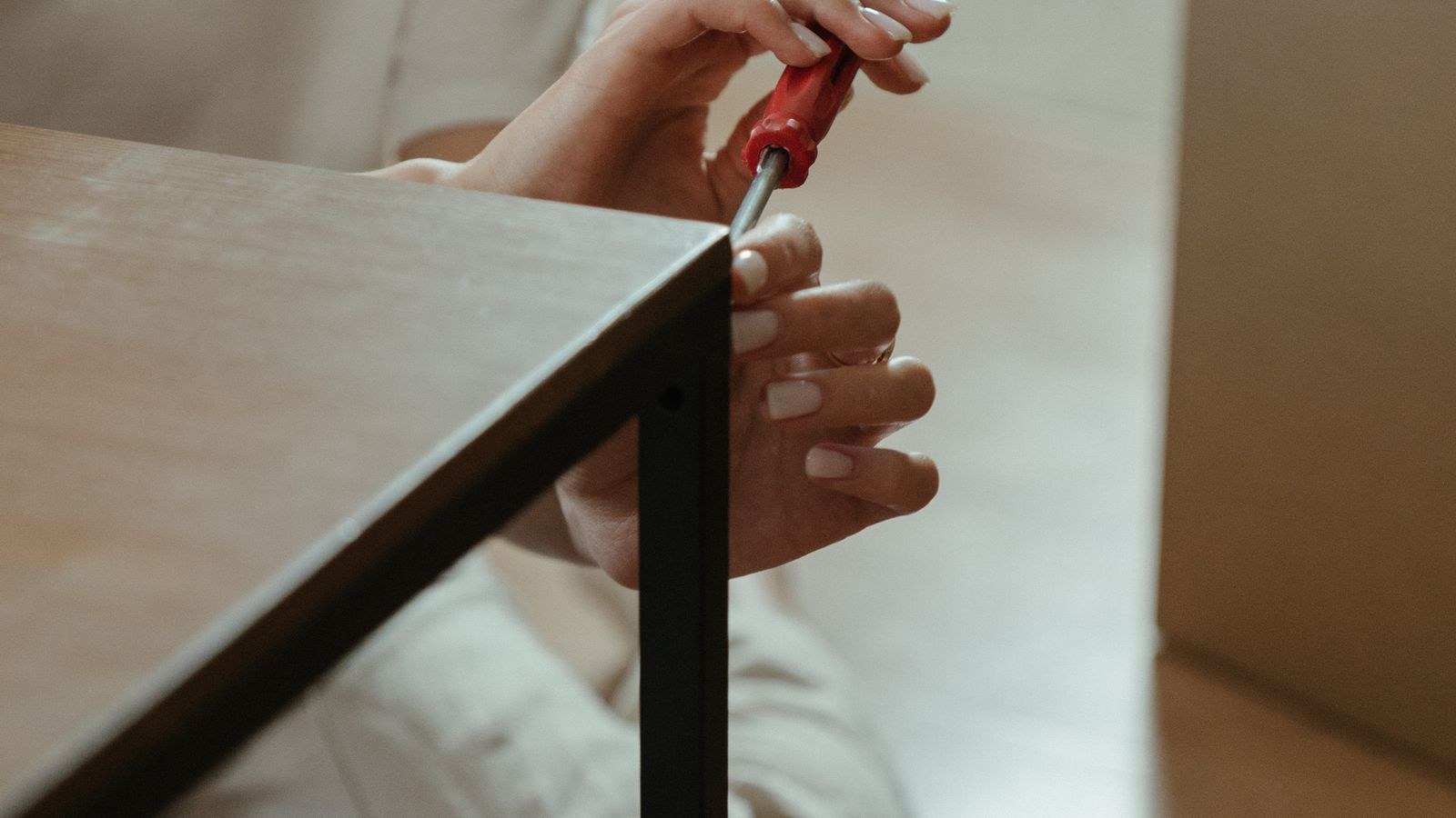 Person using a screwdriver to assemble furniture at home