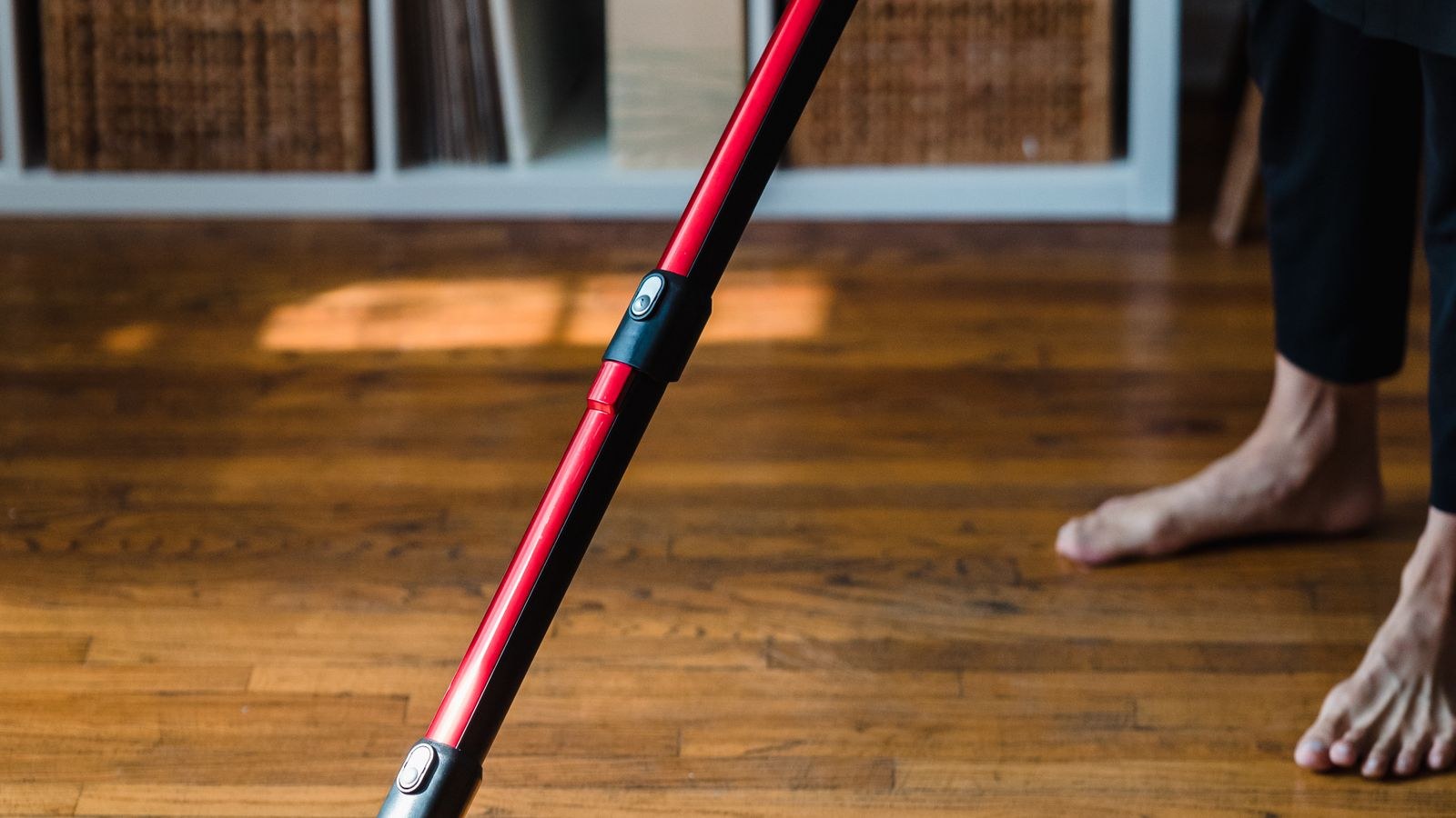 Modern vacuum cleaner being used to clean a wooden floor at home