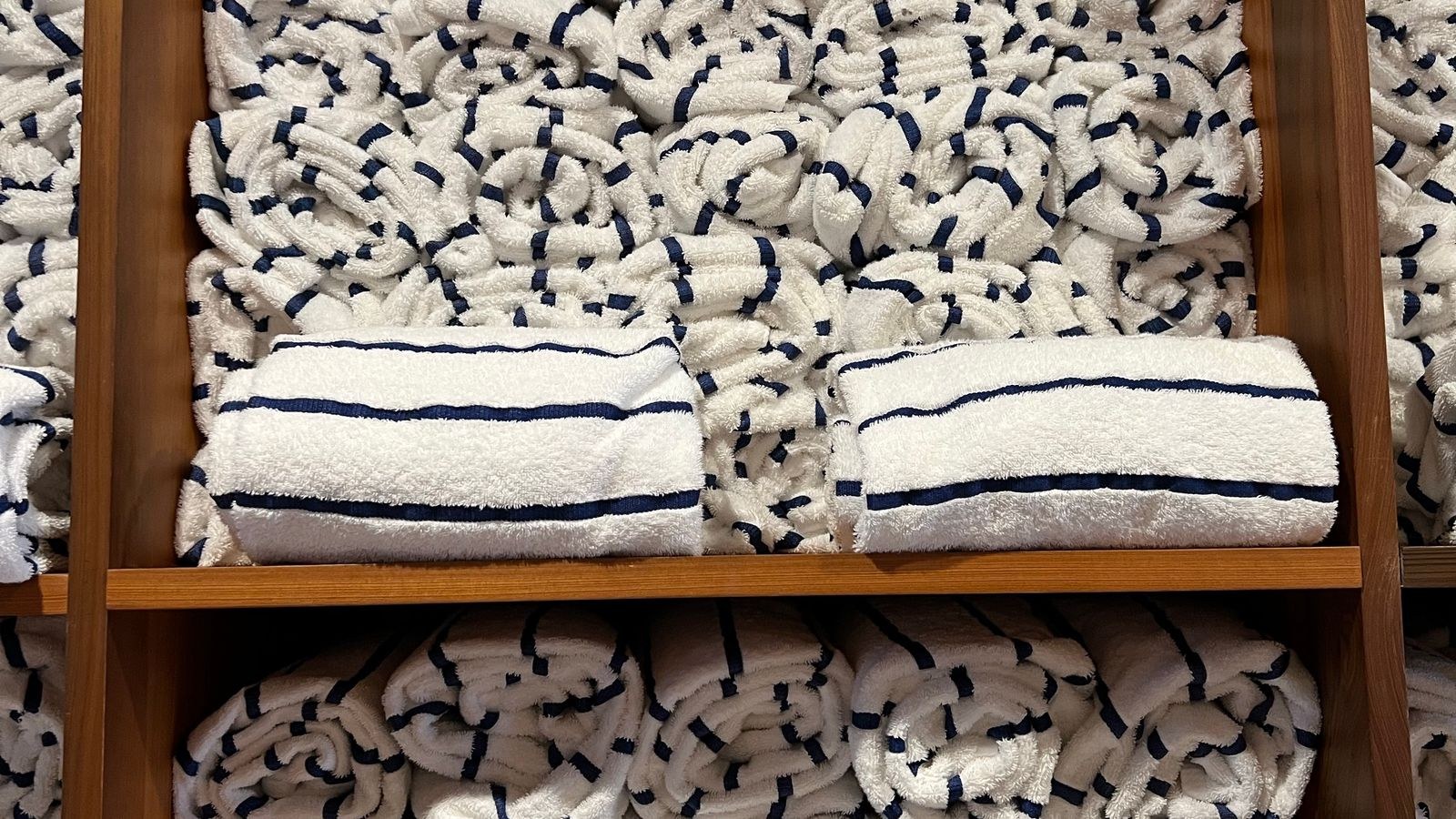 Folded striped bath towels stored on wooden bathroom shelves