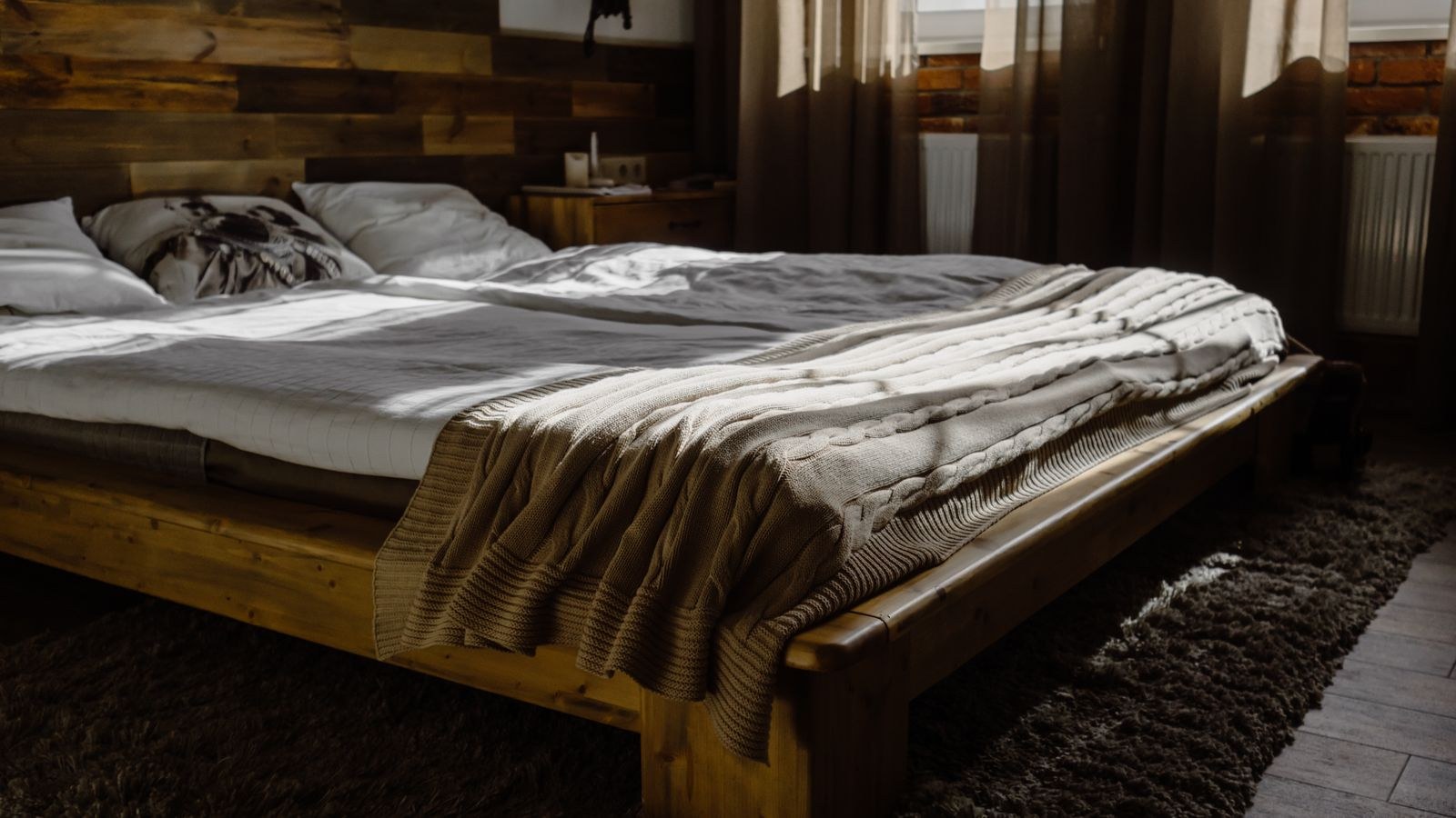 Sunlit modern bedroom with a wooden platform bed frame and cozy blankets