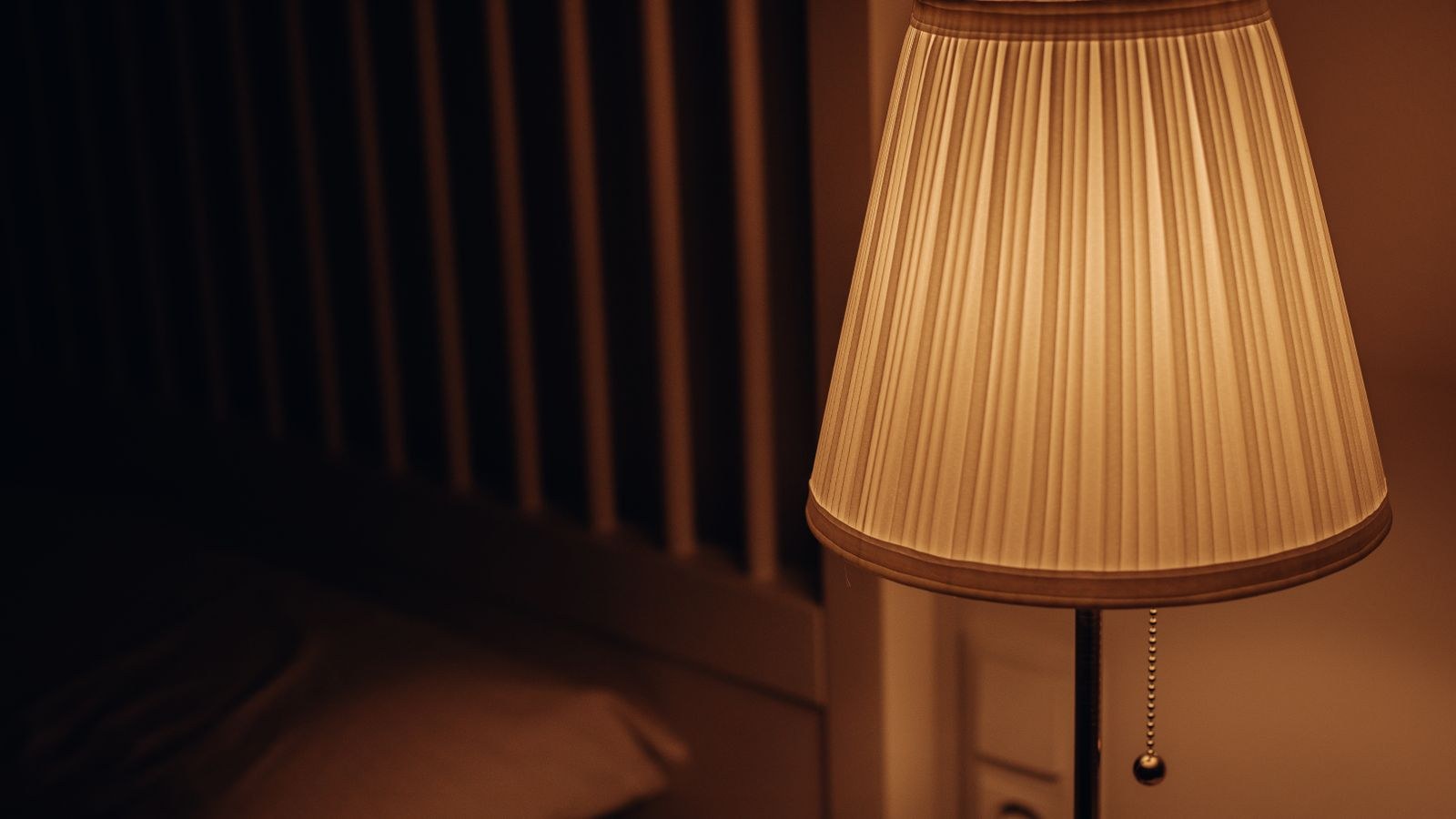 Warm bedside lamp glowing in an upstairs window at night