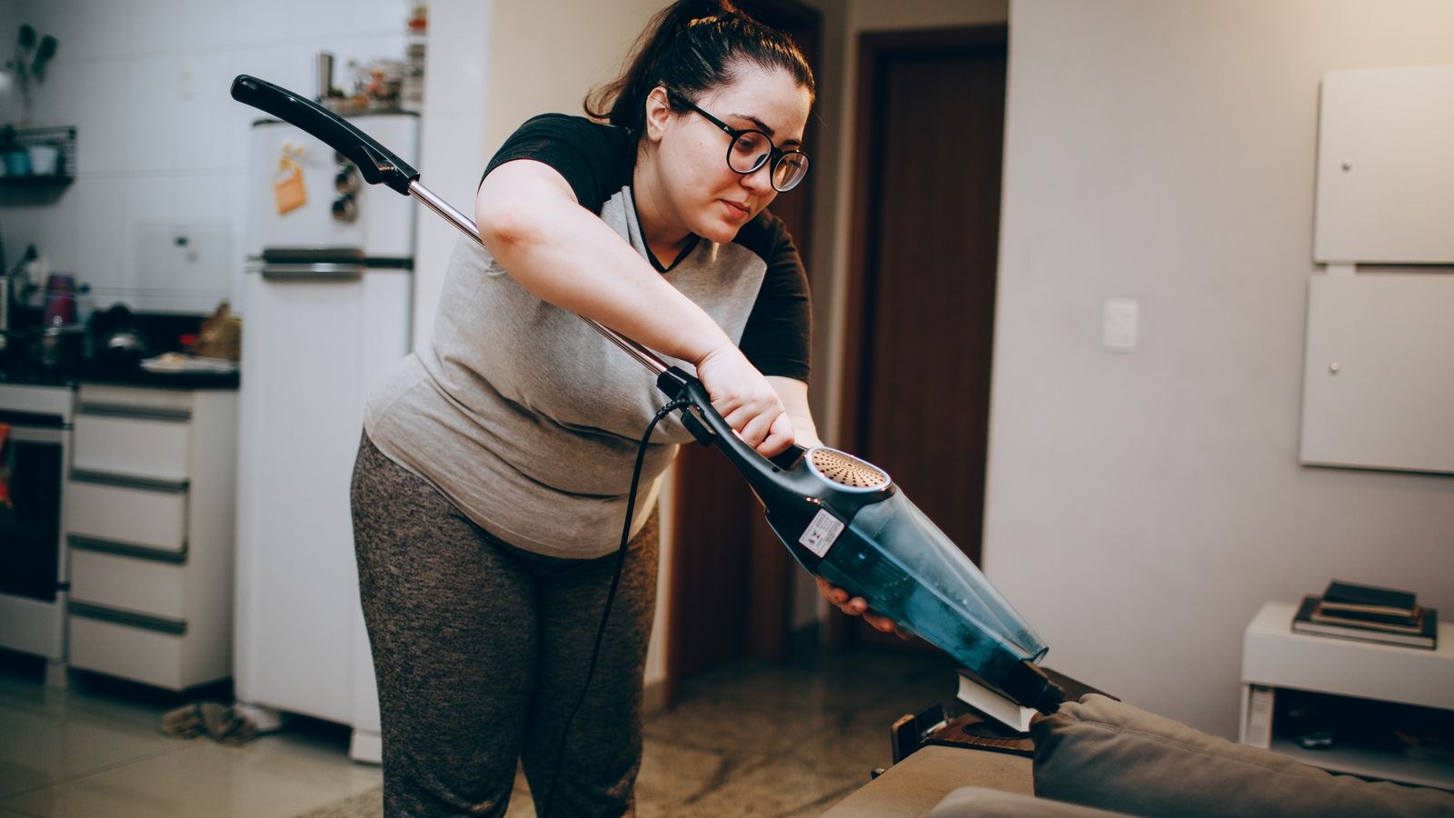 Woman cleaning a sofa with a portable upholstery and carpet cleaning tool
