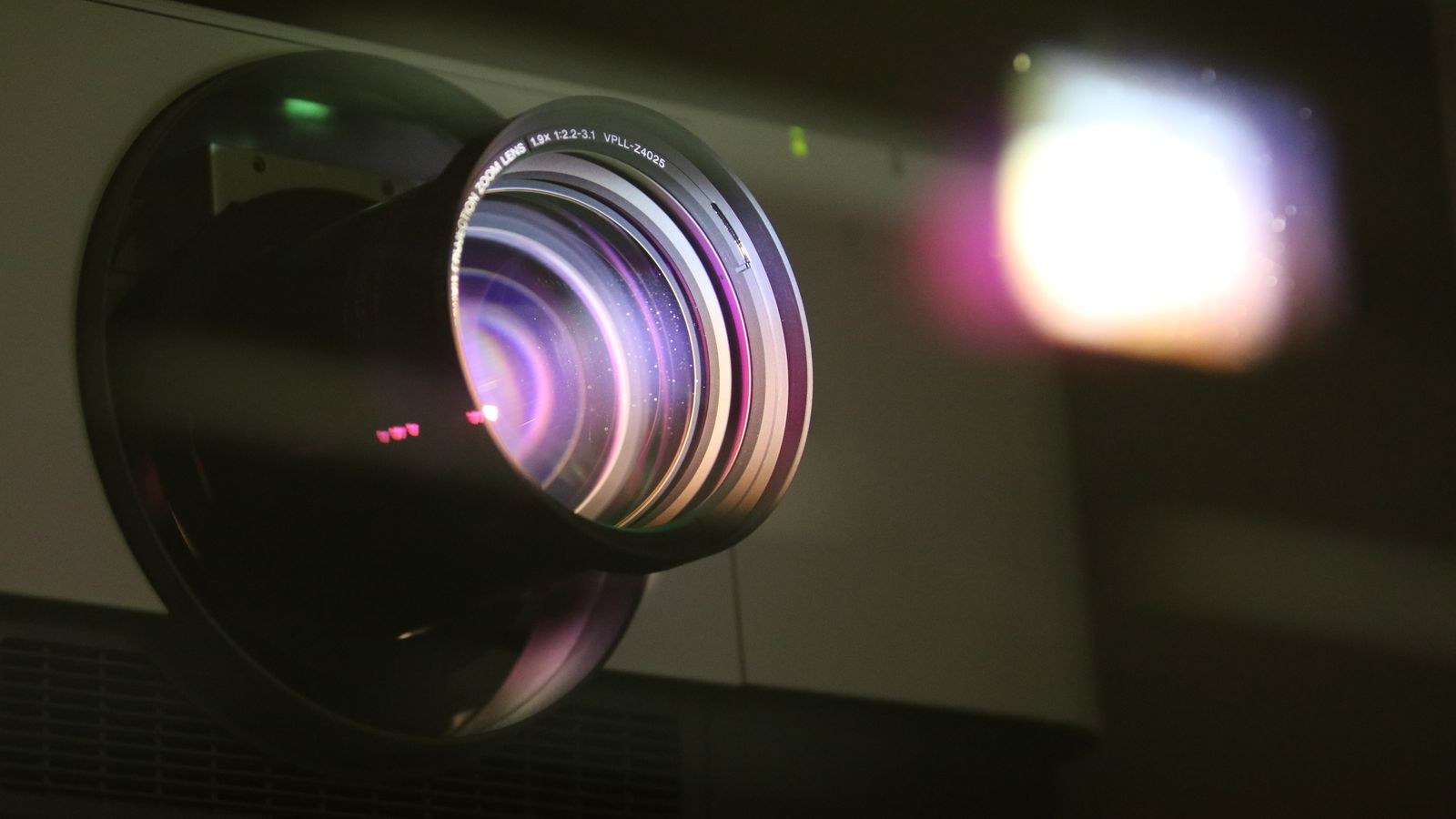 Close up of a projector lens emitting a bright beam of light