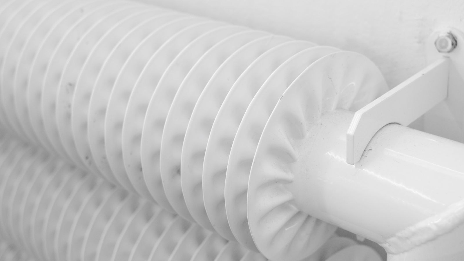 Finned oil filled radiator heater mounted against a light coloured wall