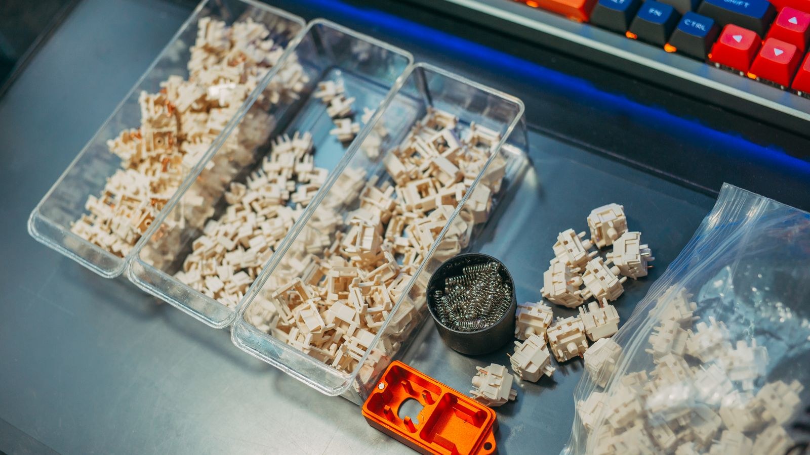 Mechanical keyboard switches and springs organised in containers on a desk