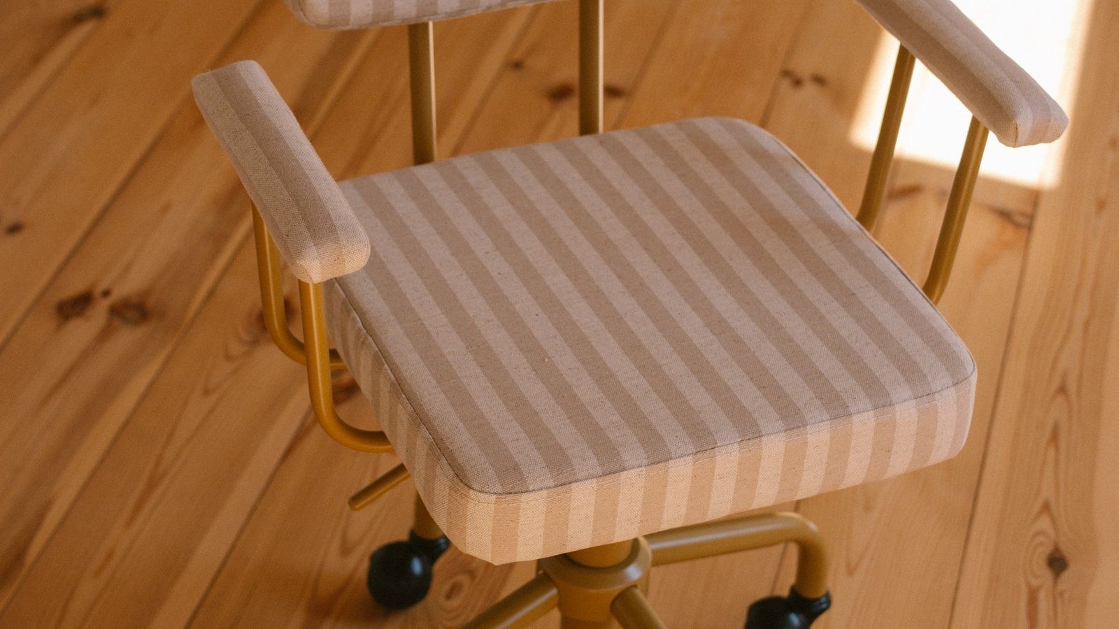 Modern striped office chair on a wooden floor in warm sunlight