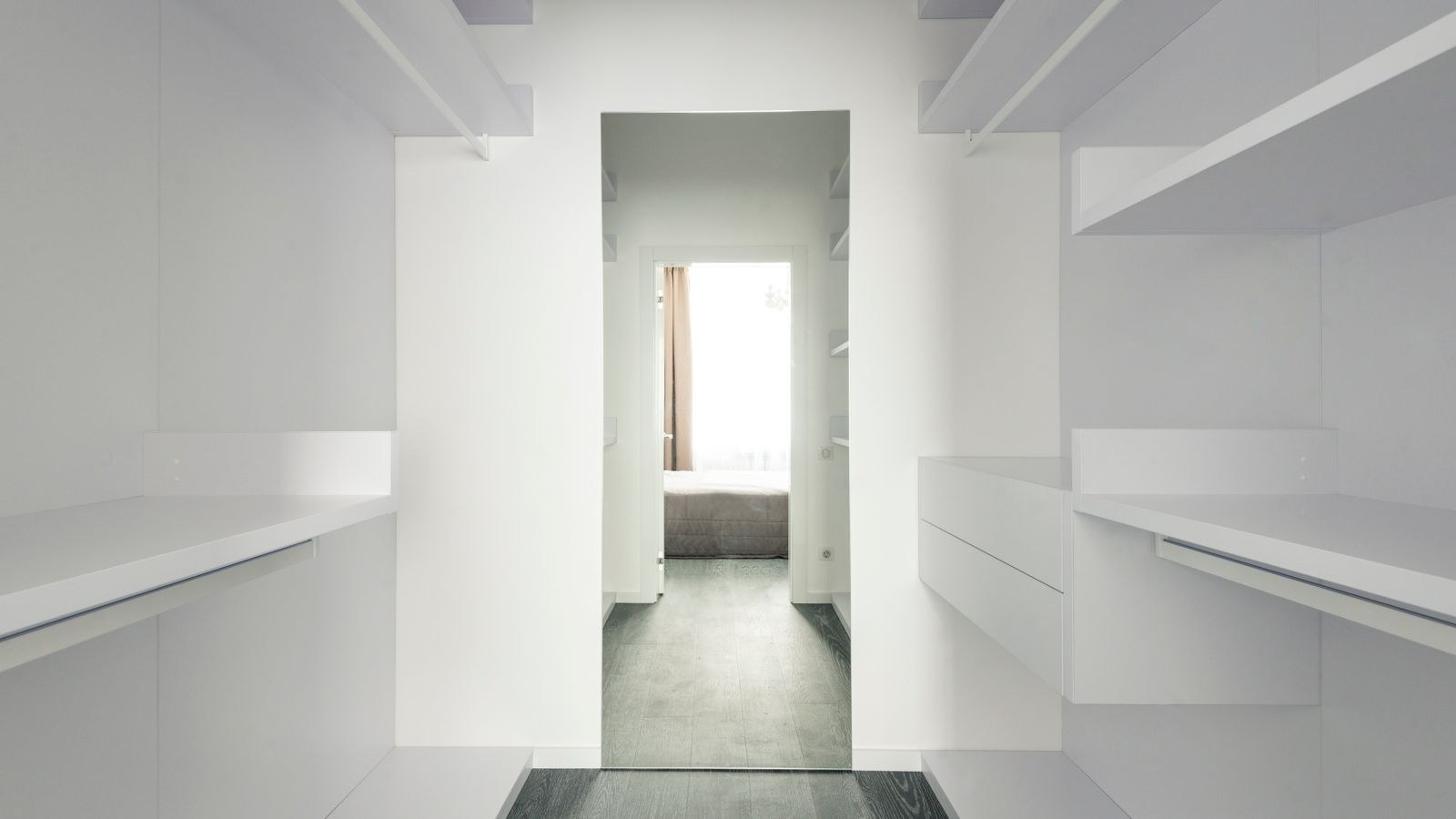 Closet shelving with folded clothes and accessories under warm LED strip lighting