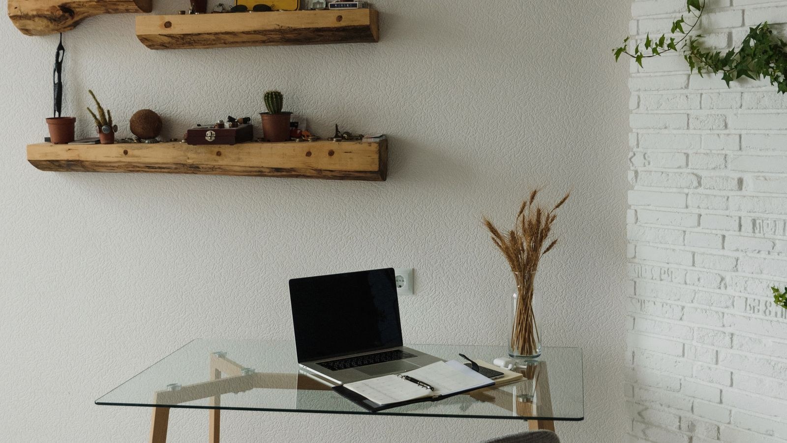 Corner workspace with a minimalist glass desk and wall mounted shelving