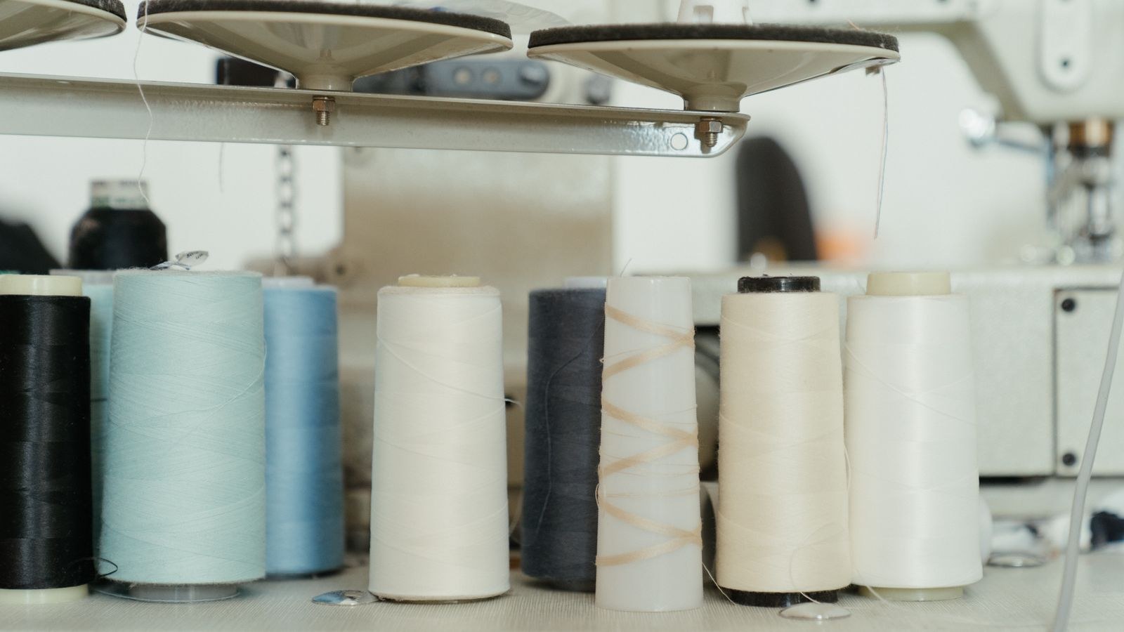 Colorful thread spools beside a sewing machine under bright craft room light