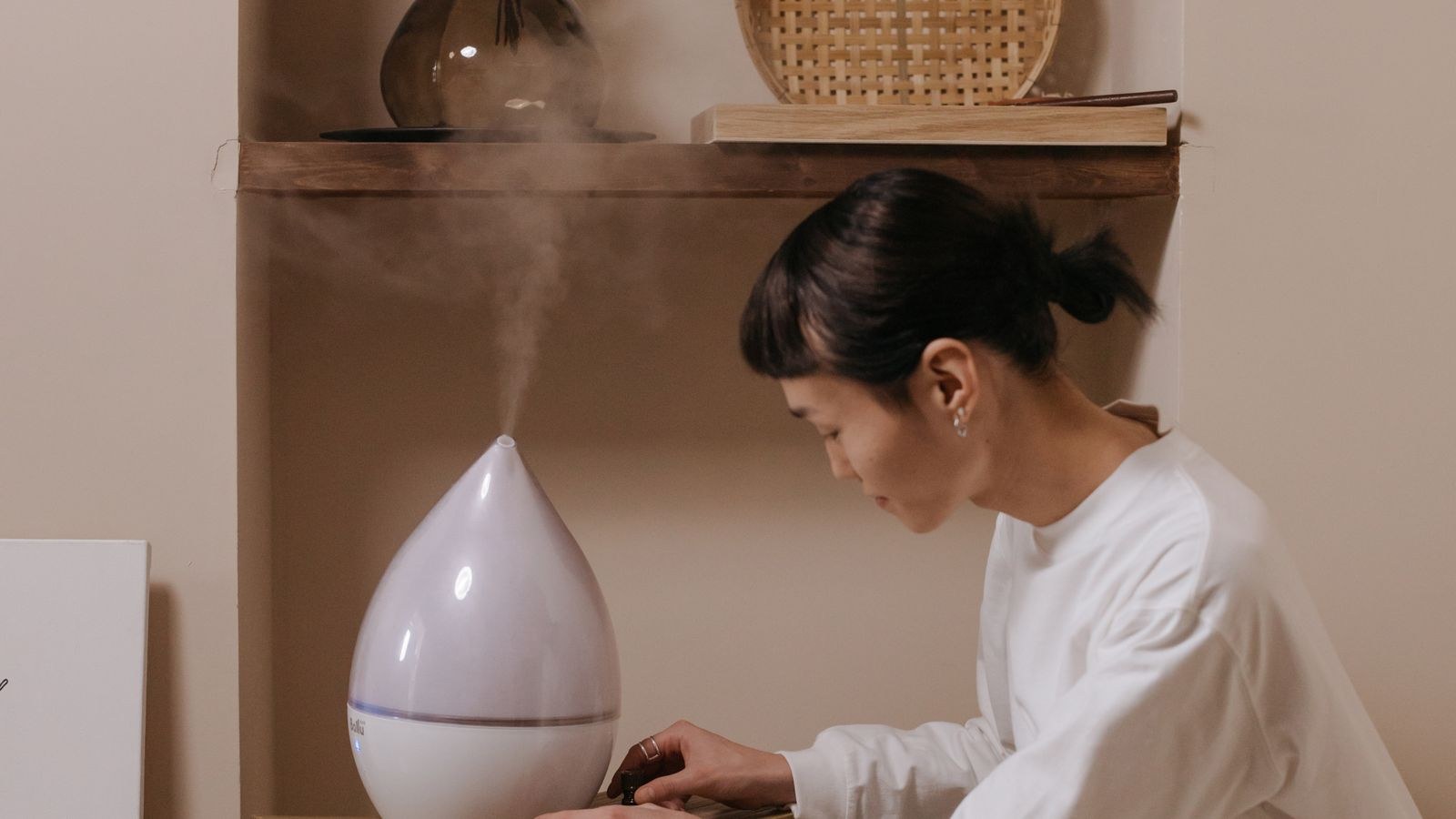 Woman adjusting a humidity control appliance in a bright indoor room