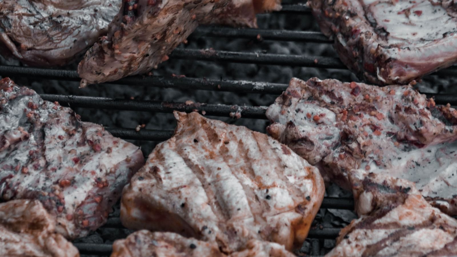 Close up of steaks cooking on a hot grill being checked for doneness