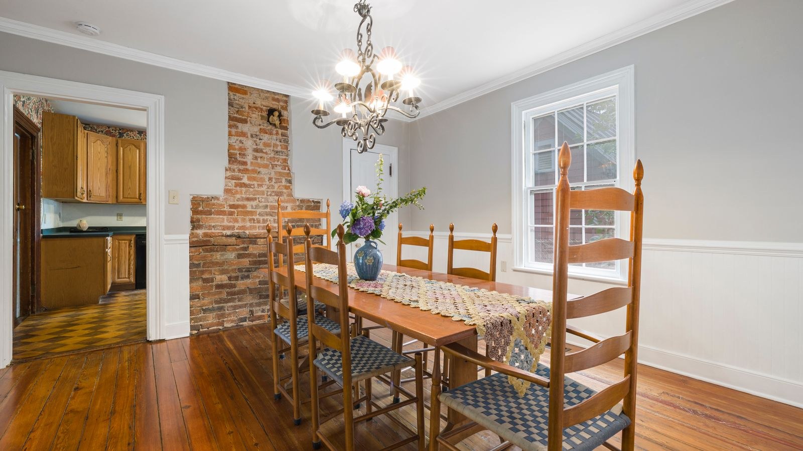 Bright dining area with brick wall, wooden table and elegant chandelier