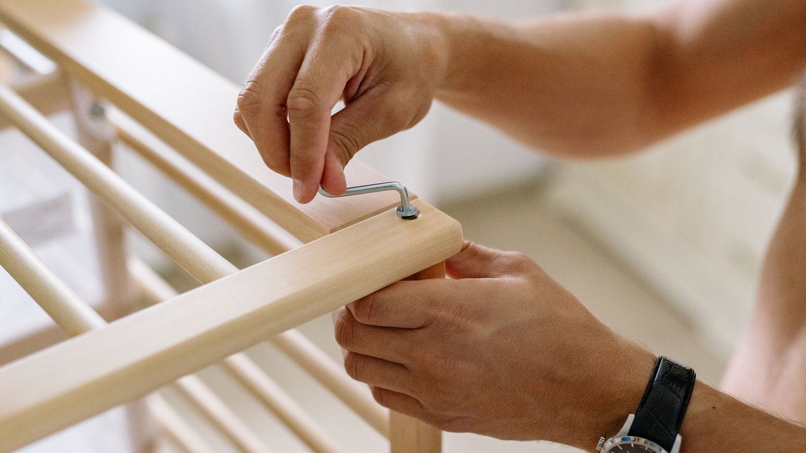 Using an Allen wrench to take apart a piece of wooden furniture