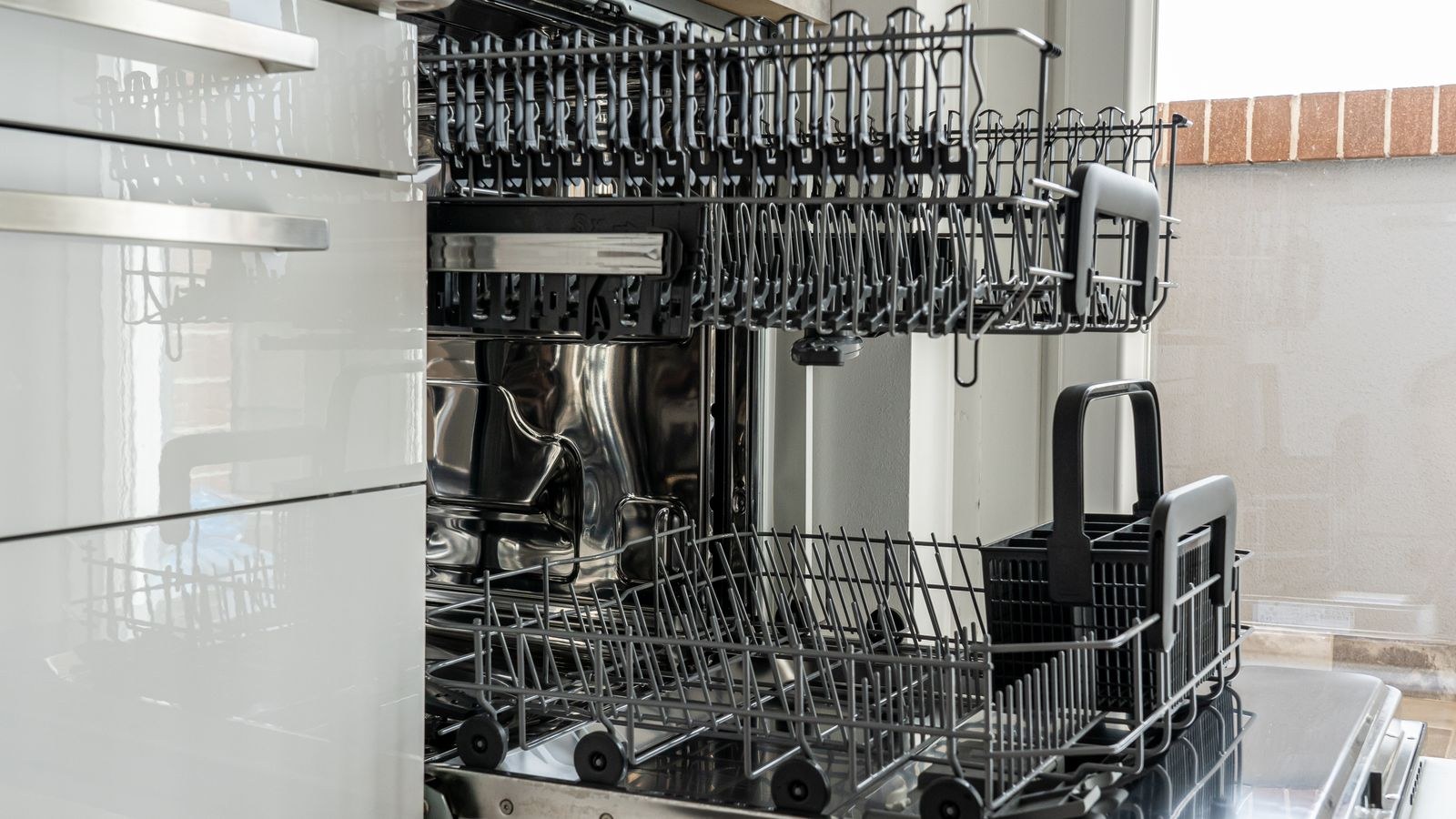 Open empty stainless steel dishwasher in a bright modern kitchen