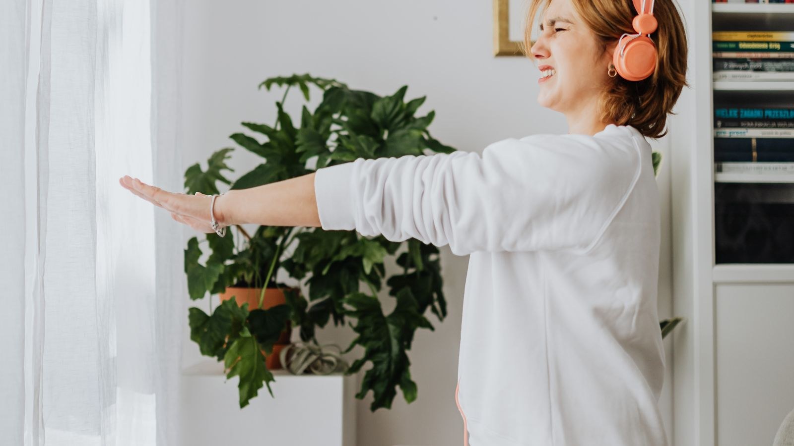 Woman stretching in a bright home office next to a laptop on the desk