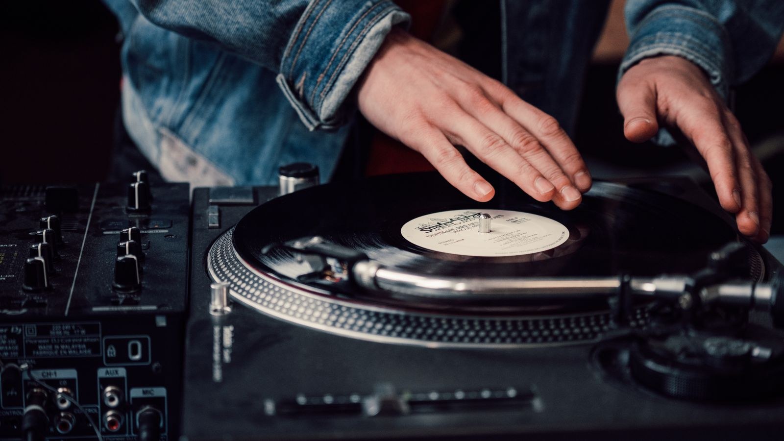Turntable connected to a phono preamp and amplifier on a wooden shelf