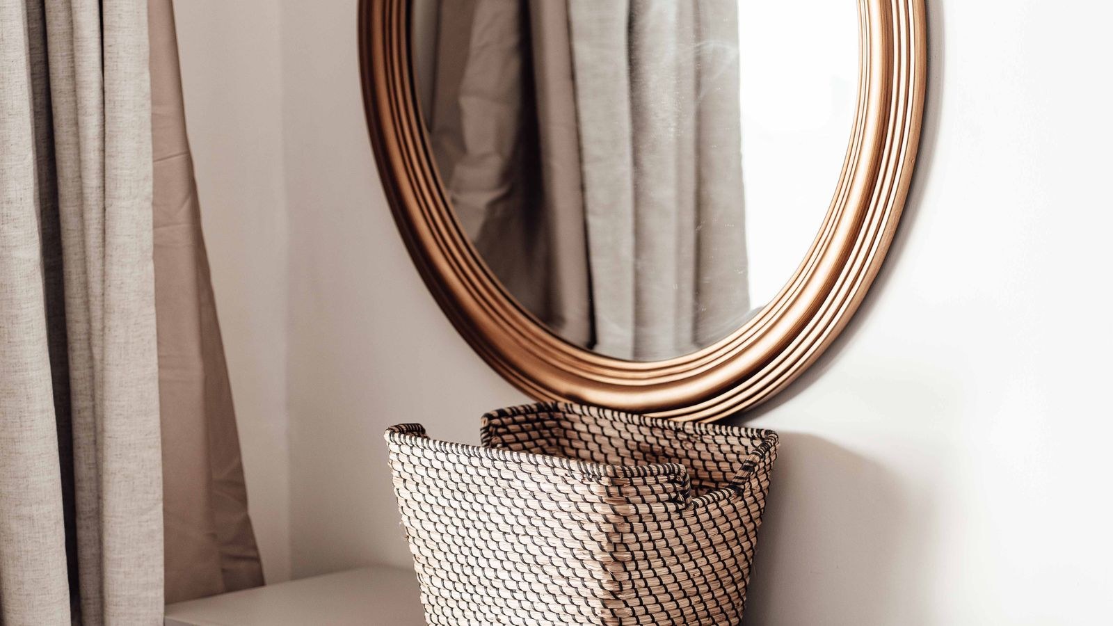 Modern dresser with round mirror above it and a storage basket alongside