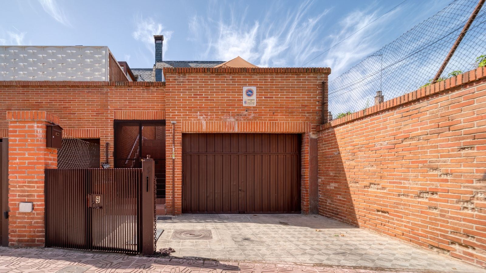 House driveway with garage door and secure gate covered by outdoor camera