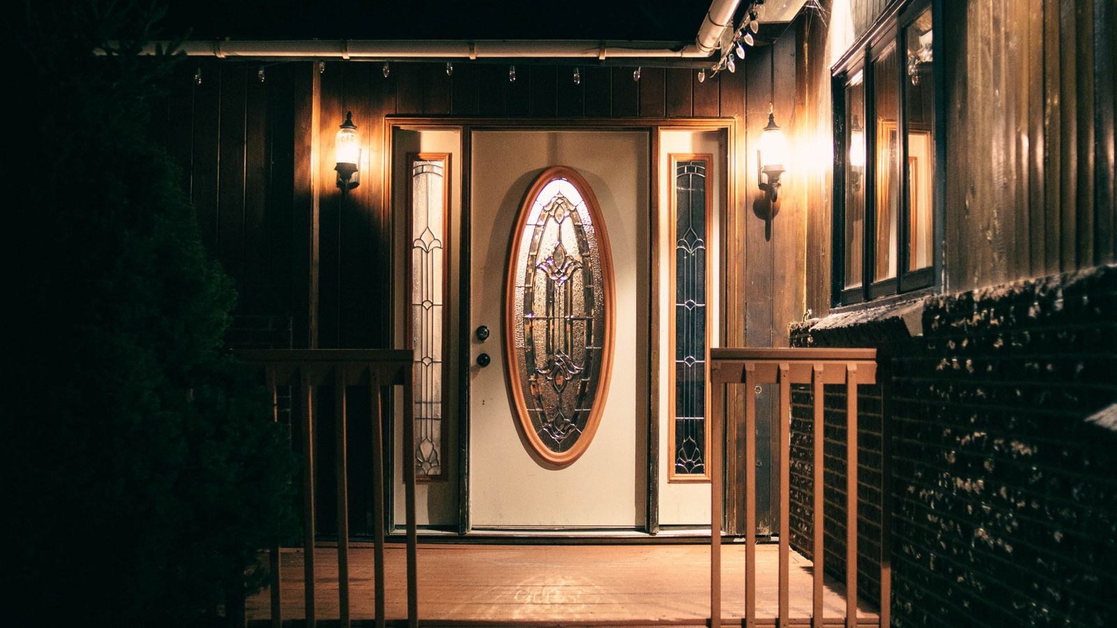 Warmly lit house entrance with outdoor lighting glowing after sunset