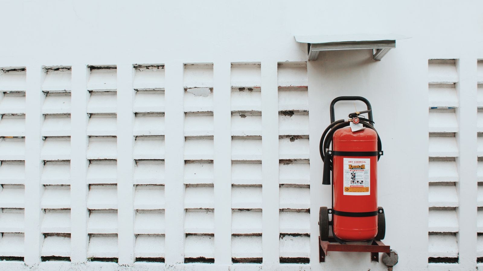 Red fire extinguisher mounted on a wall ready for emergency use