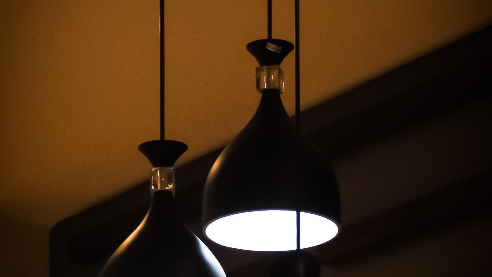 Black pendant light fixtures hanging indoors and casting a warm glow