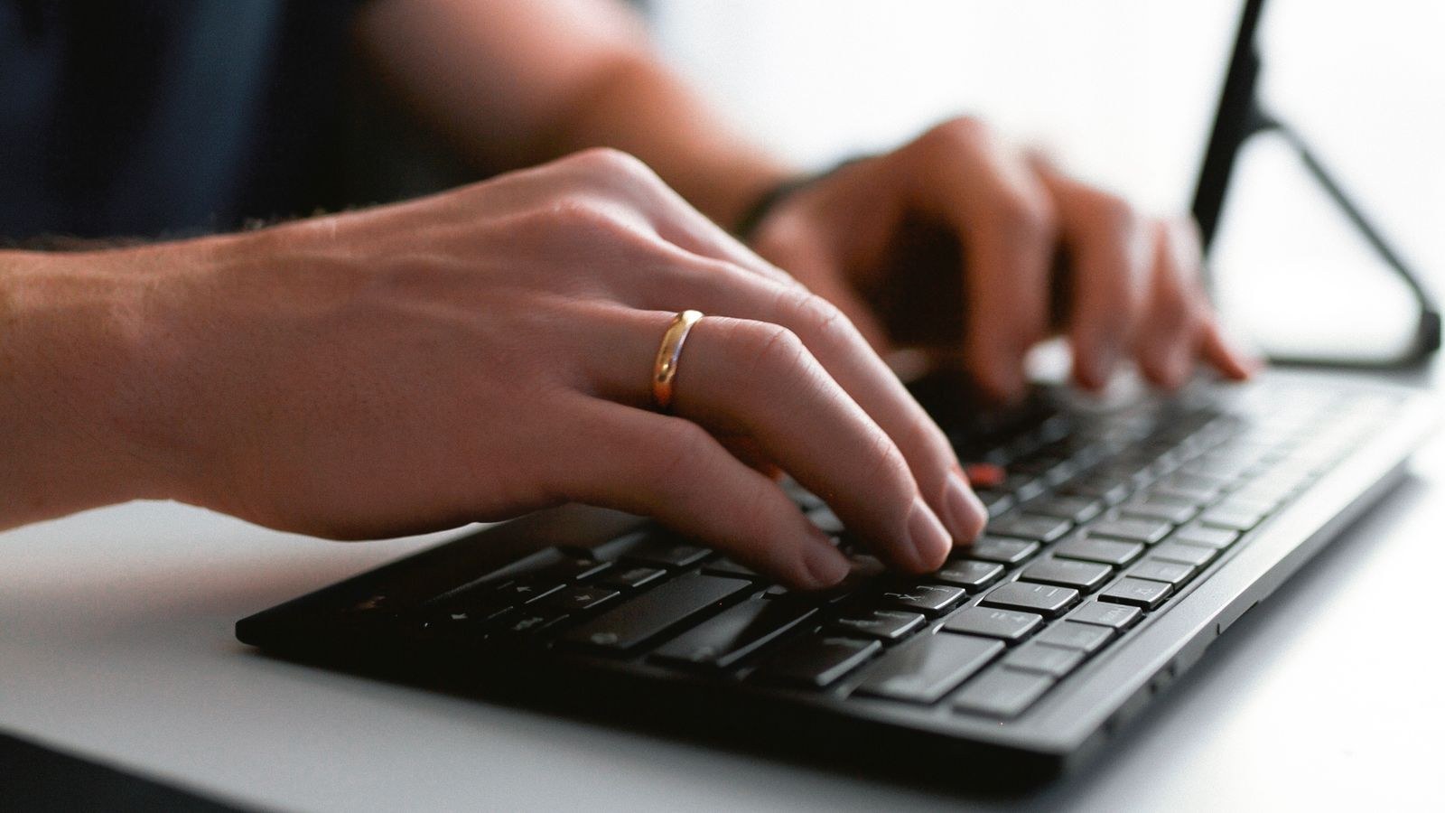 Person typing on an ergonomic keyboard at a desk with neutral wrist posture