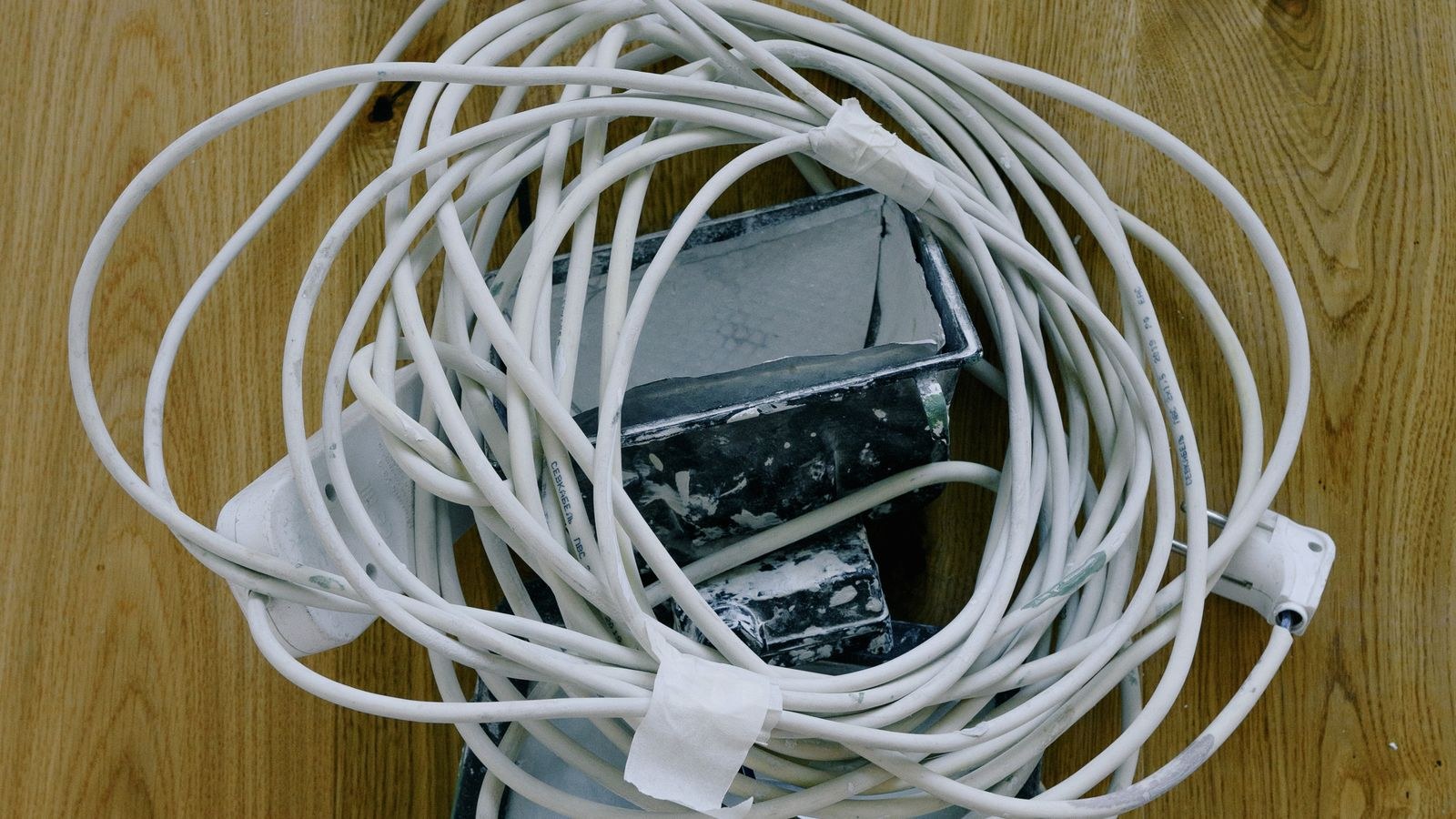 White electrical extension cord and plug laid out on a wooden surface during a repair