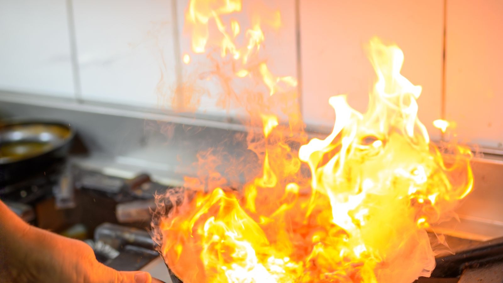 Flames rising from a pan on a gas stove during cooking