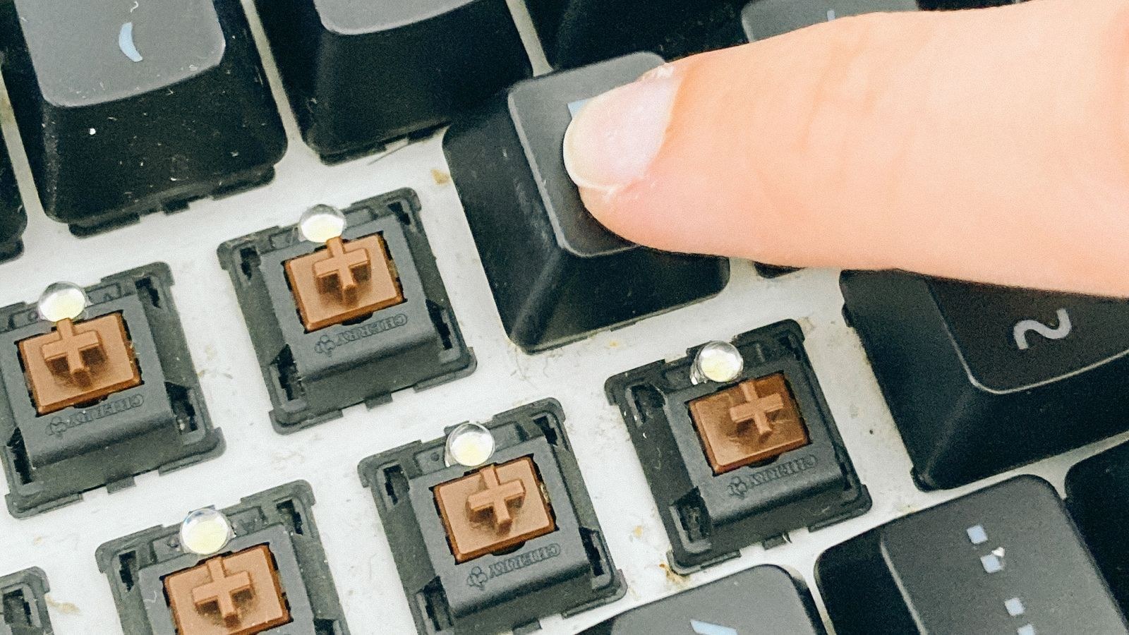 Hands pressing keycaps back onto a mechanical keyboard after cleaning