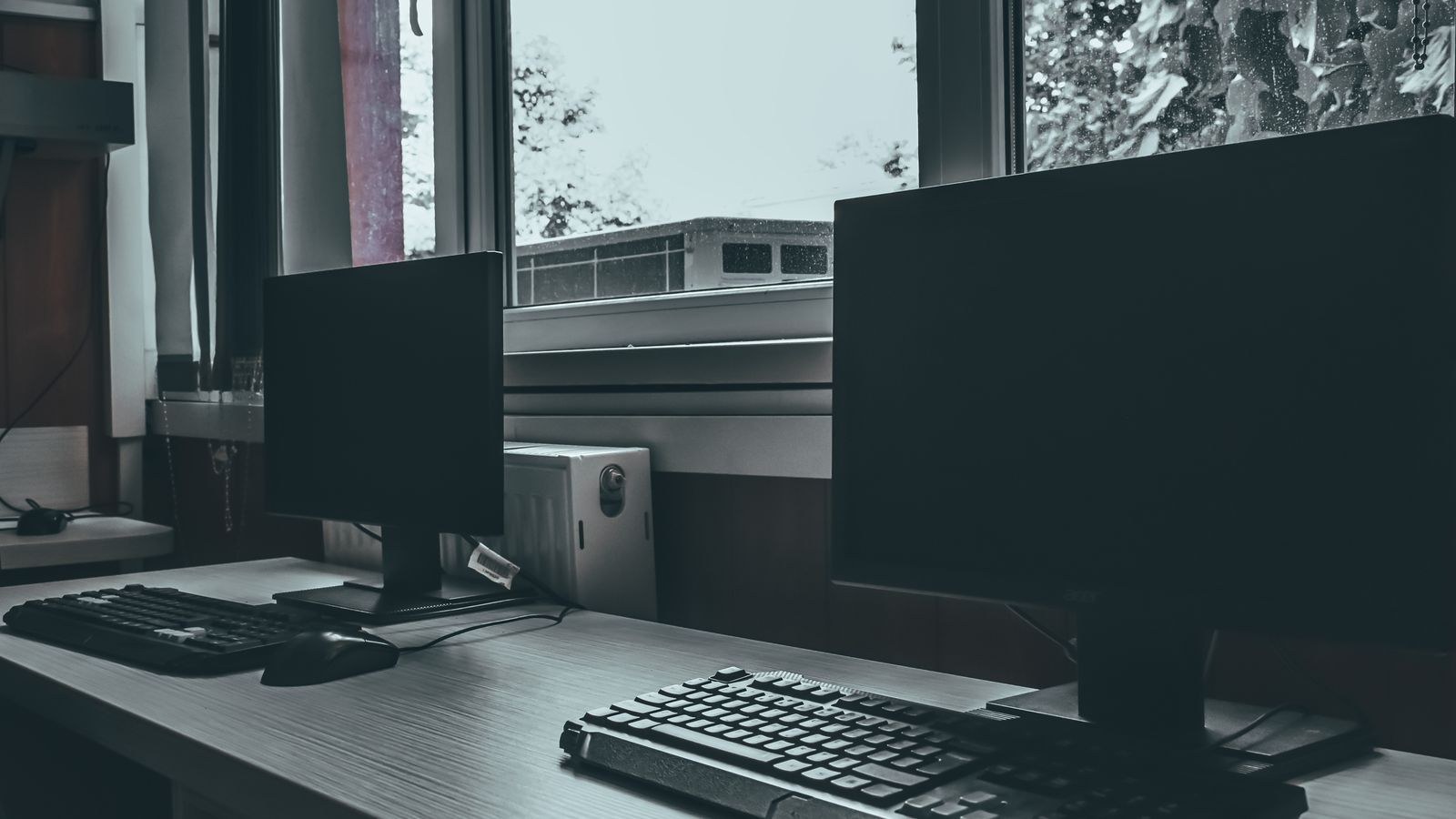 Computer monitors with blank black screens showing no signal on a desk