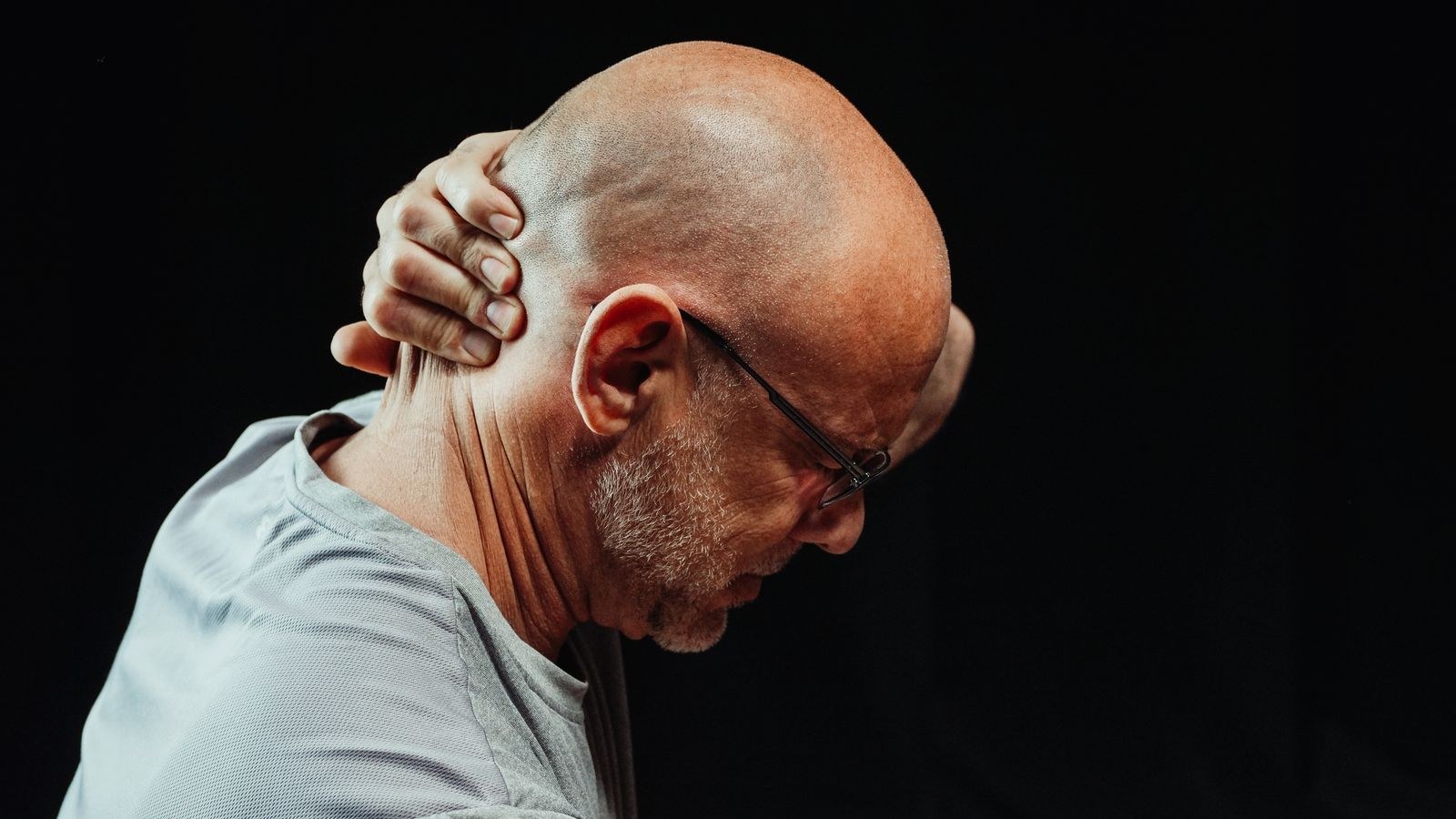 Man holding his neck in discomfort from forward head posture caused by desk work