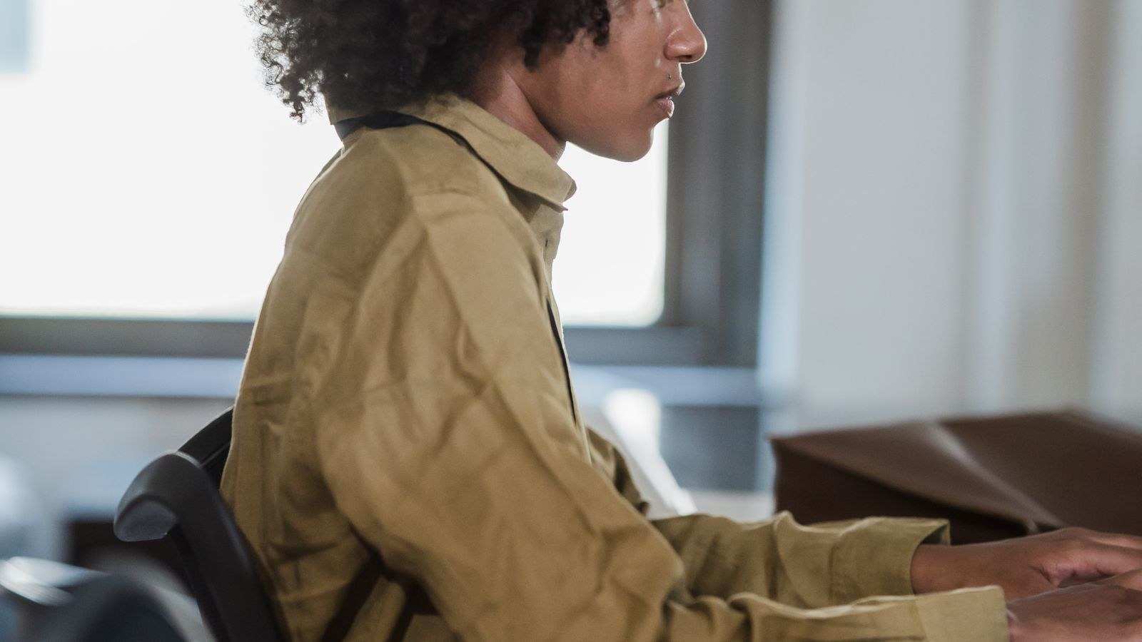 Woman working at a desk with her monitor positioned at eye level to prevent tech neck