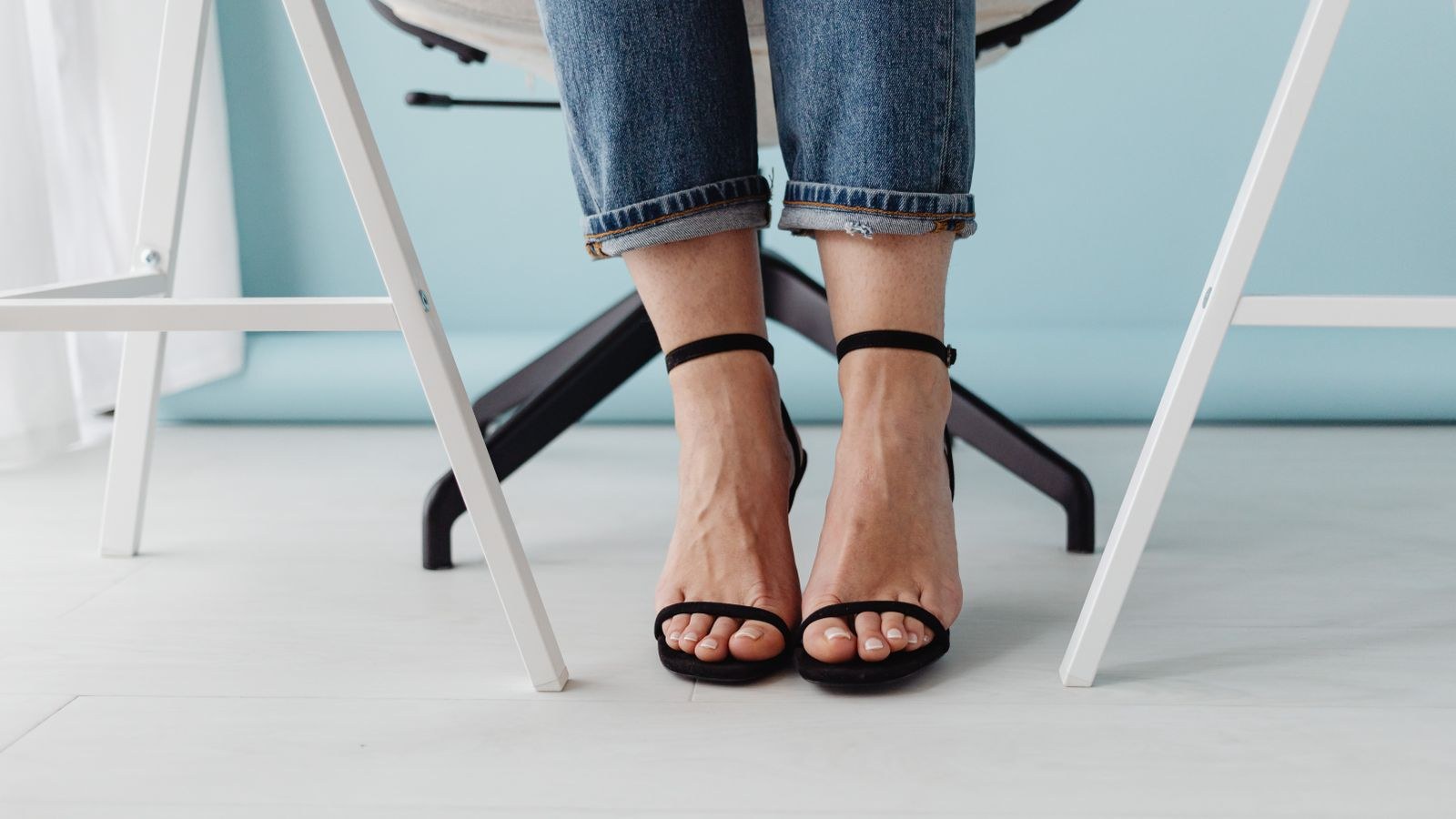 Close up of a seated person's legs and feet beside a chair in an office