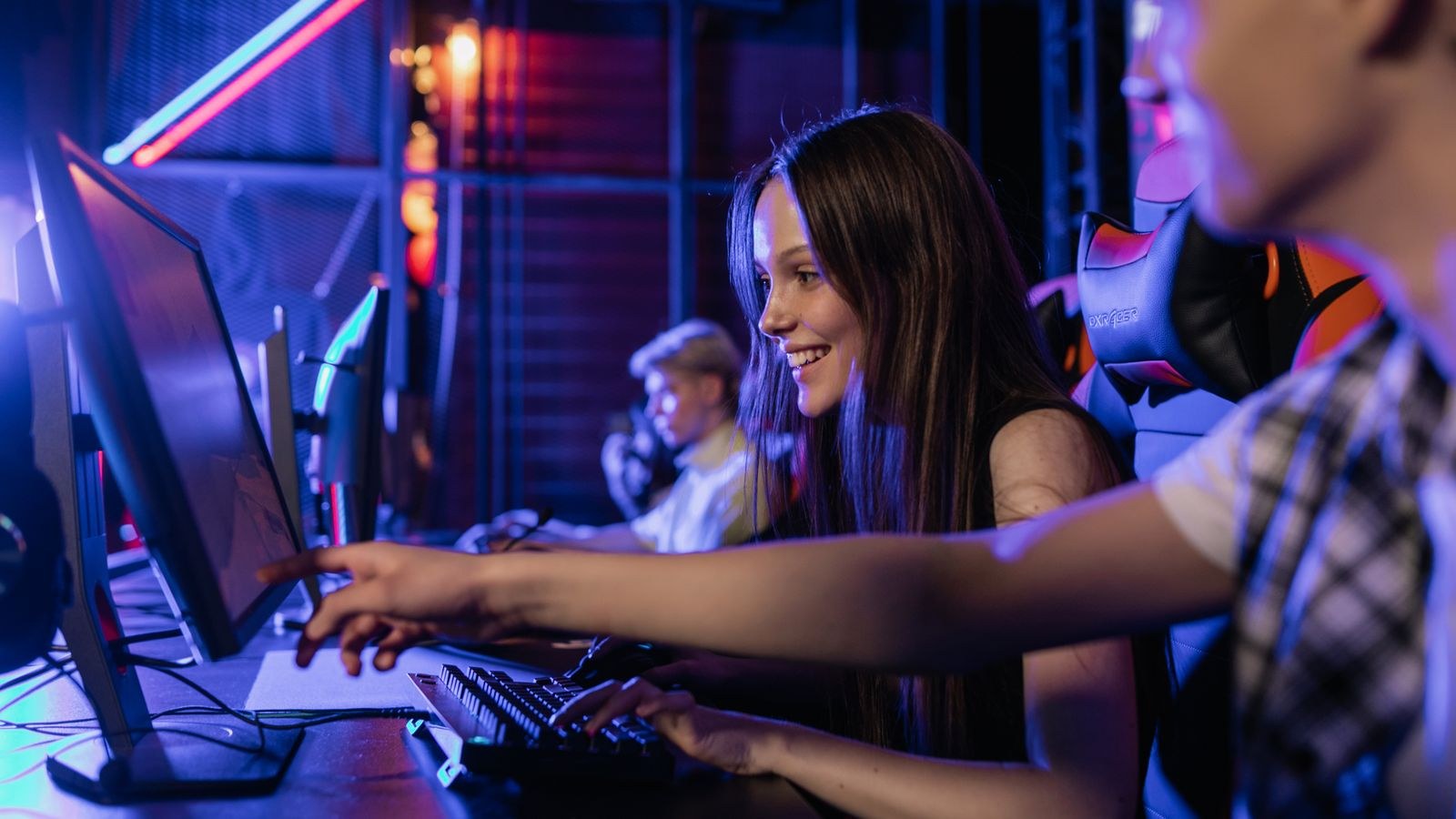 Group of teenagers gaming together on computers in comfortable chairs