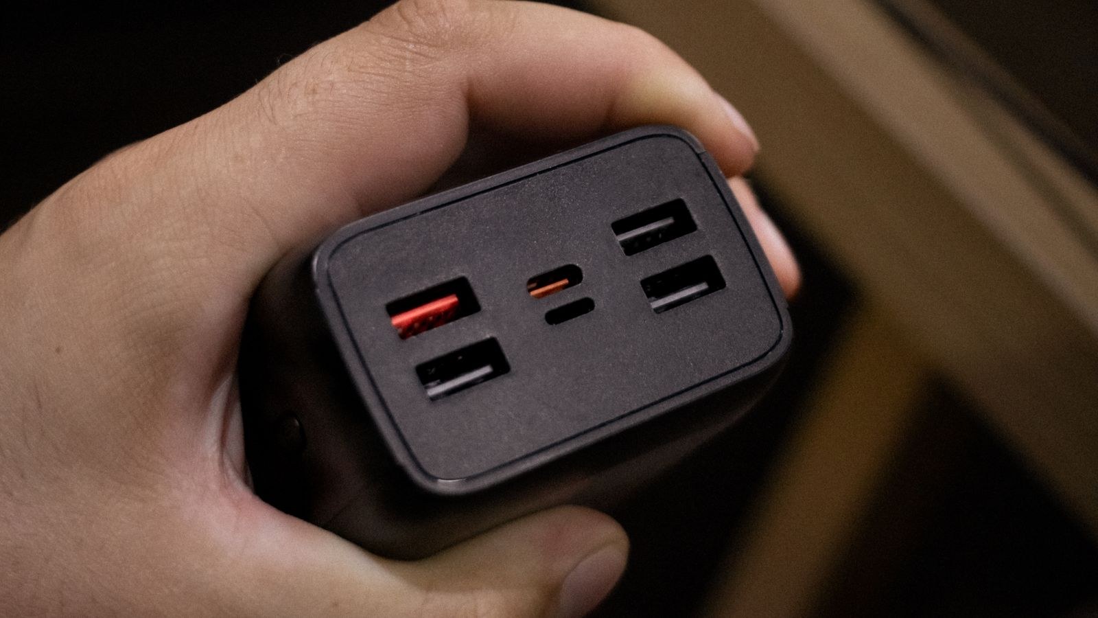 Hand holding a multi port USB power adapter showing its charging ports