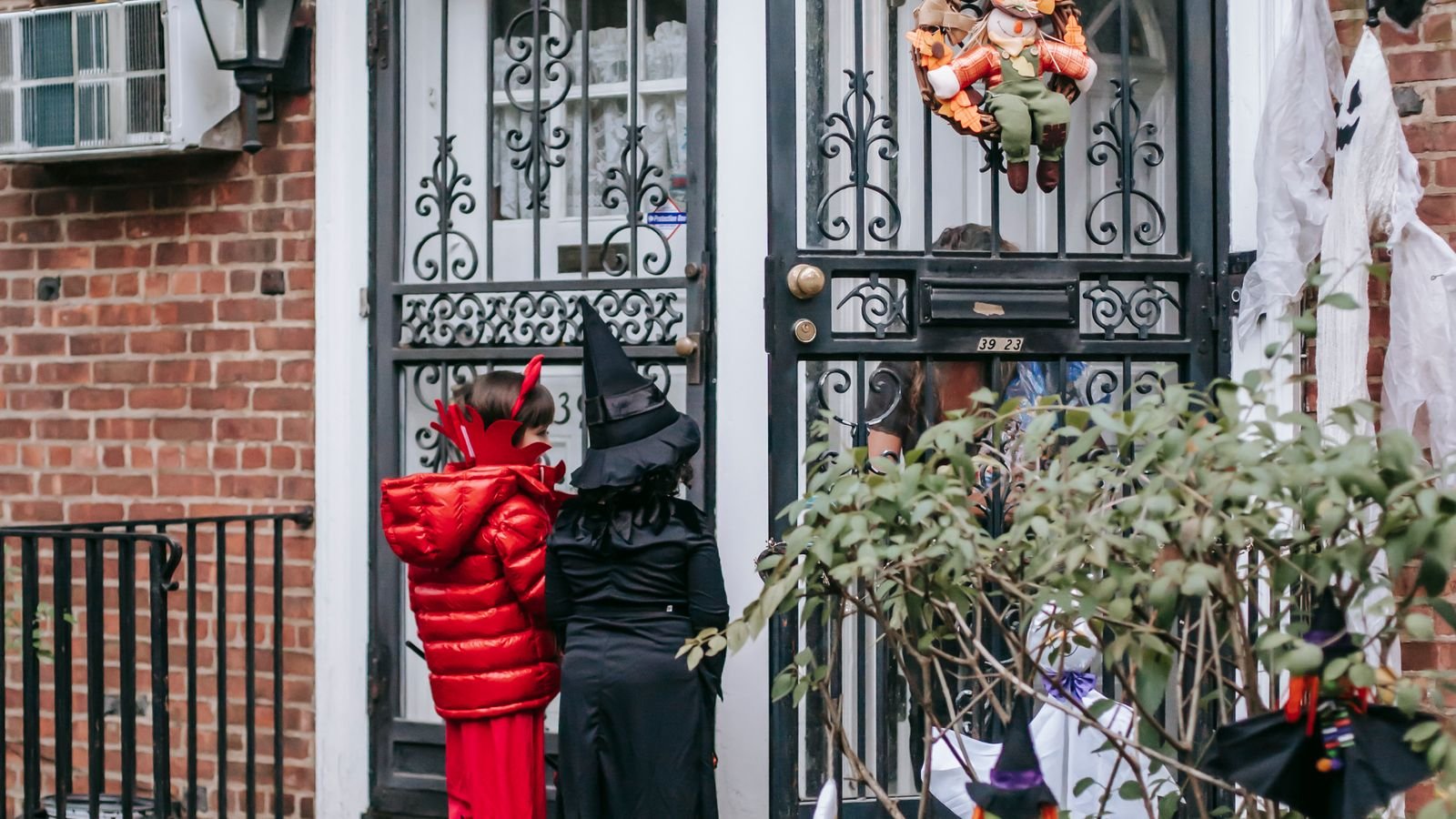 Children in Halloween costumes trick or treating at a decorated front door
