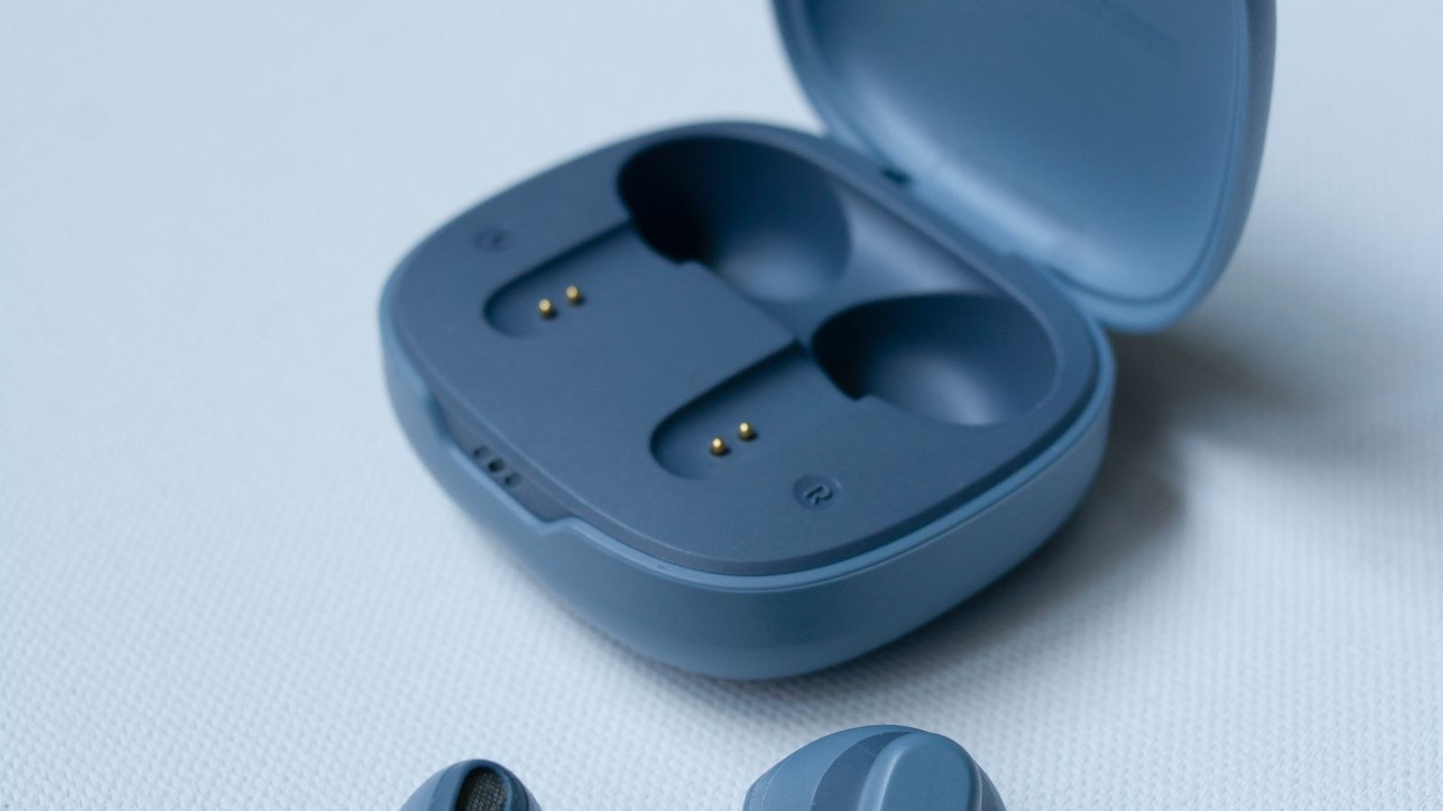 Wireless in-ear headphones with an open charging case on a white surface