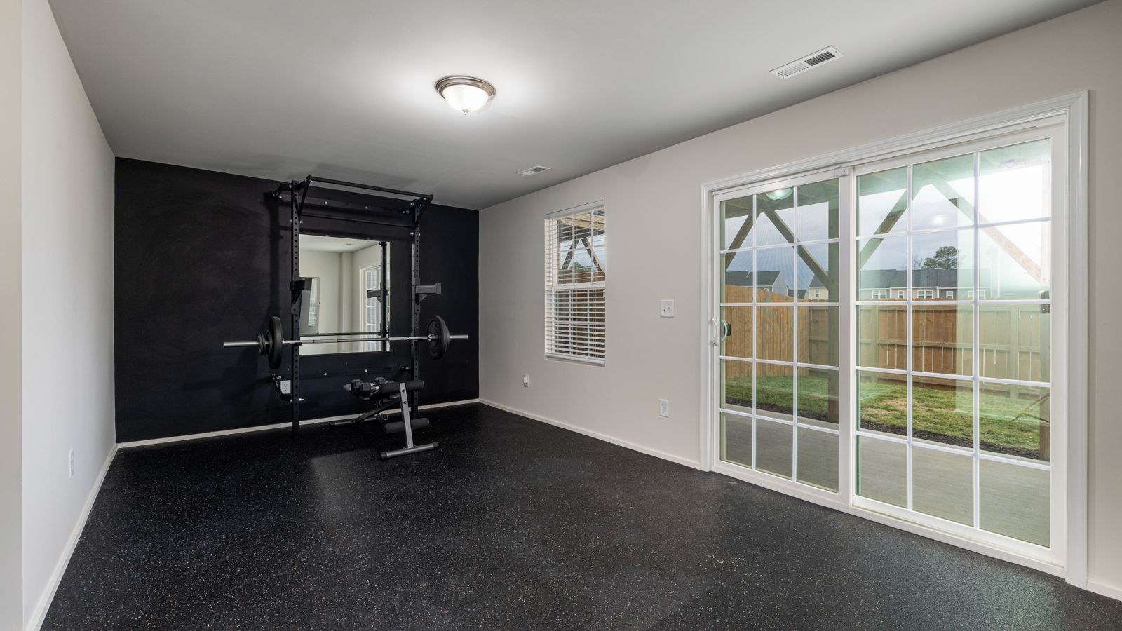Home gym with weightlifting equipment and a bright mirrored wall