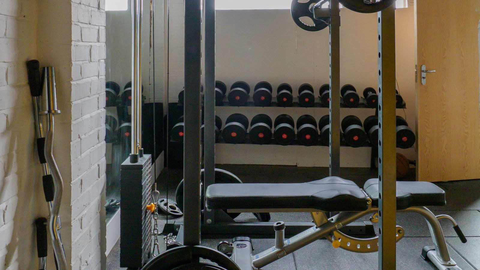 Garage home gym with bench press dumbbells and overhead lighting