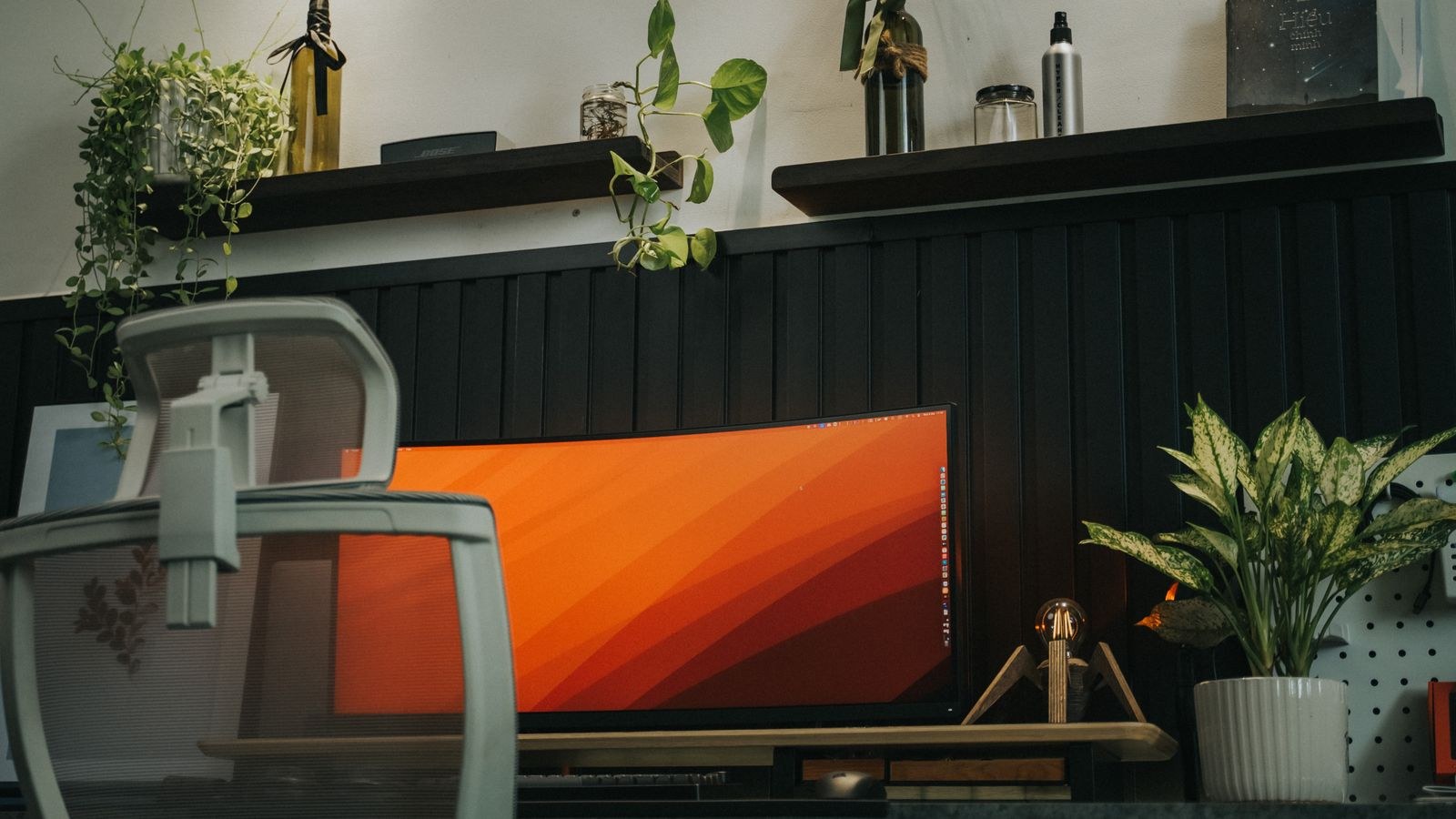 Stylish home office with curved monitor, ergonomic chair and indoor plants