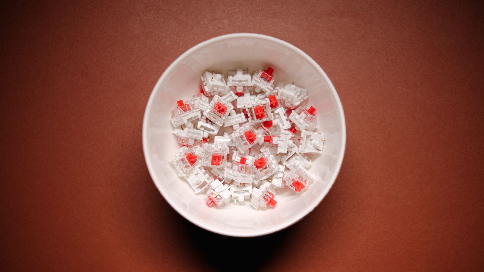 Mechanical keyboard switches collected in a bowl on a wooden surface
