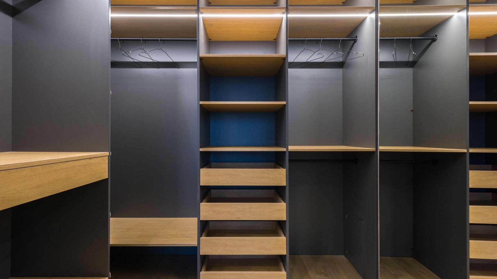 Spacious modern walk-in closet with wooden shelving and warm lighting