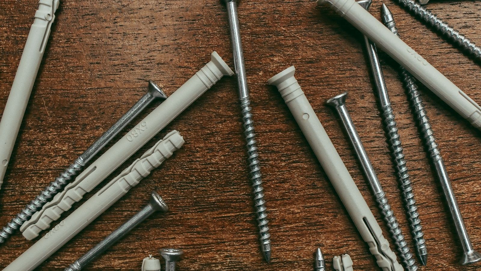 Screws and wall anchors laid out on a wooden table for furniture anchoring