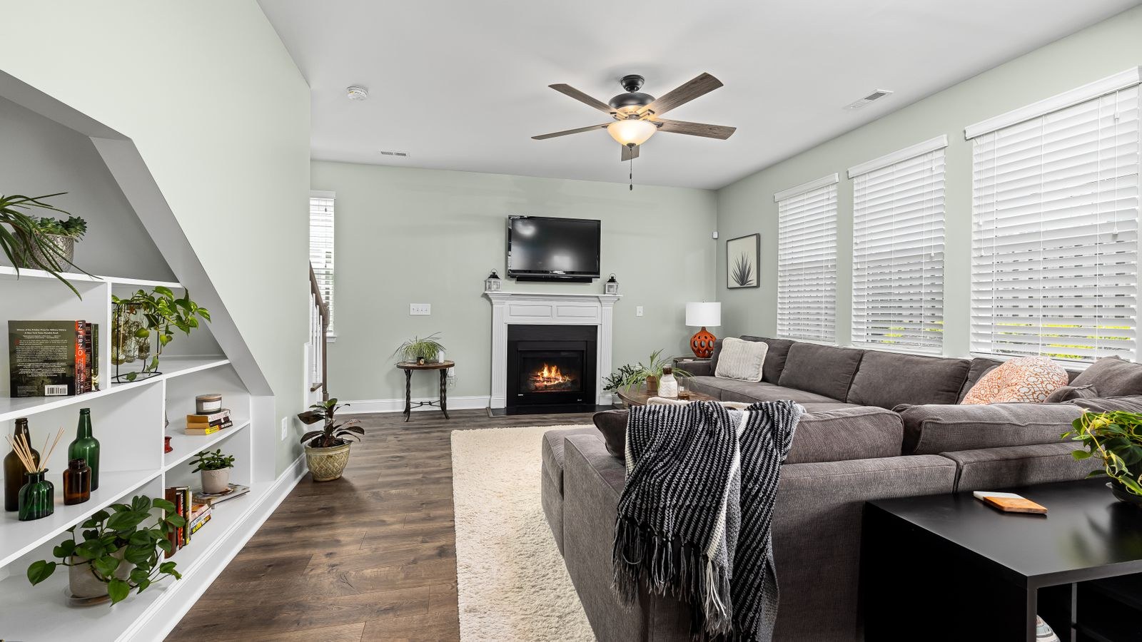 Living room with a large sectional sofa, fireplace and indoor plants
