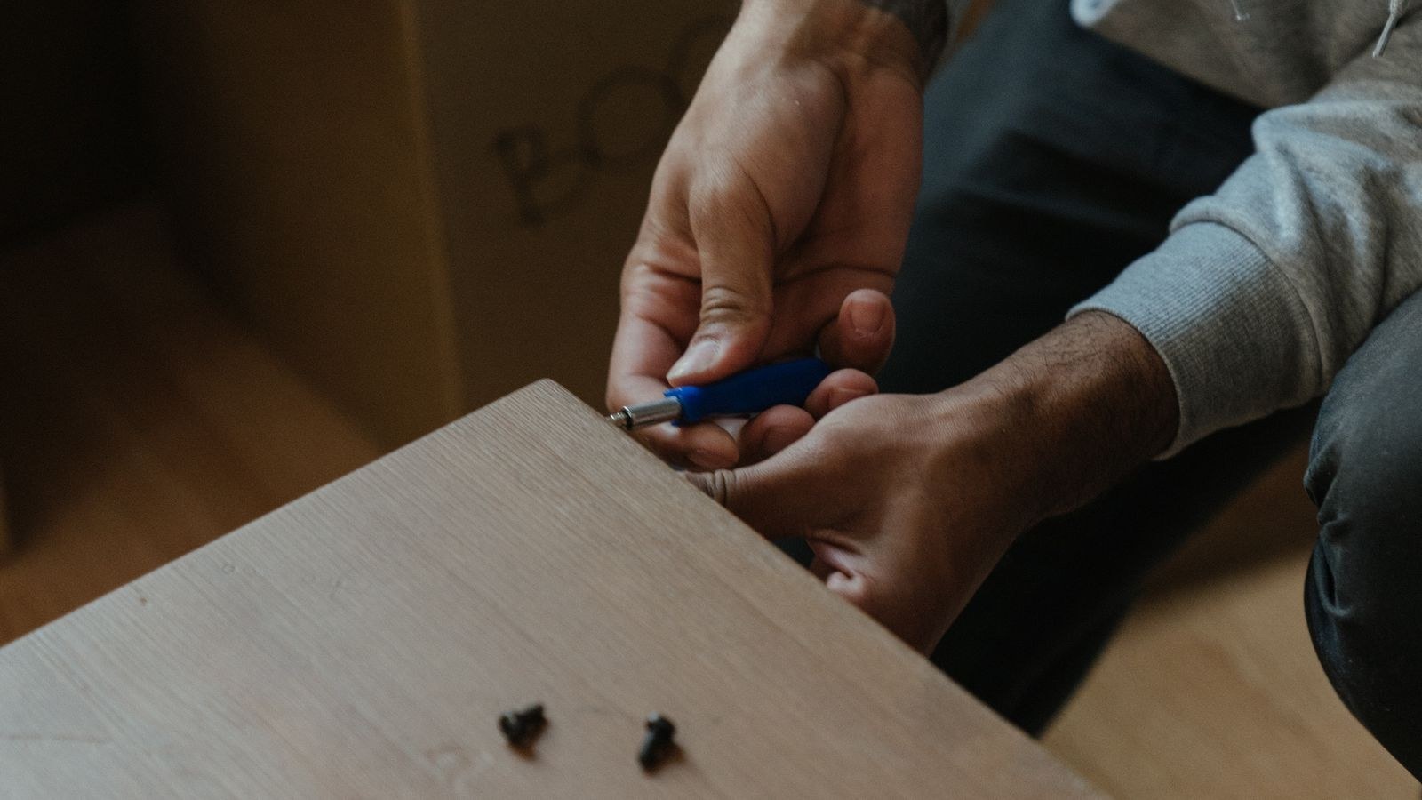 Man assembling flat-pack furniture in a newly furnished apartment
